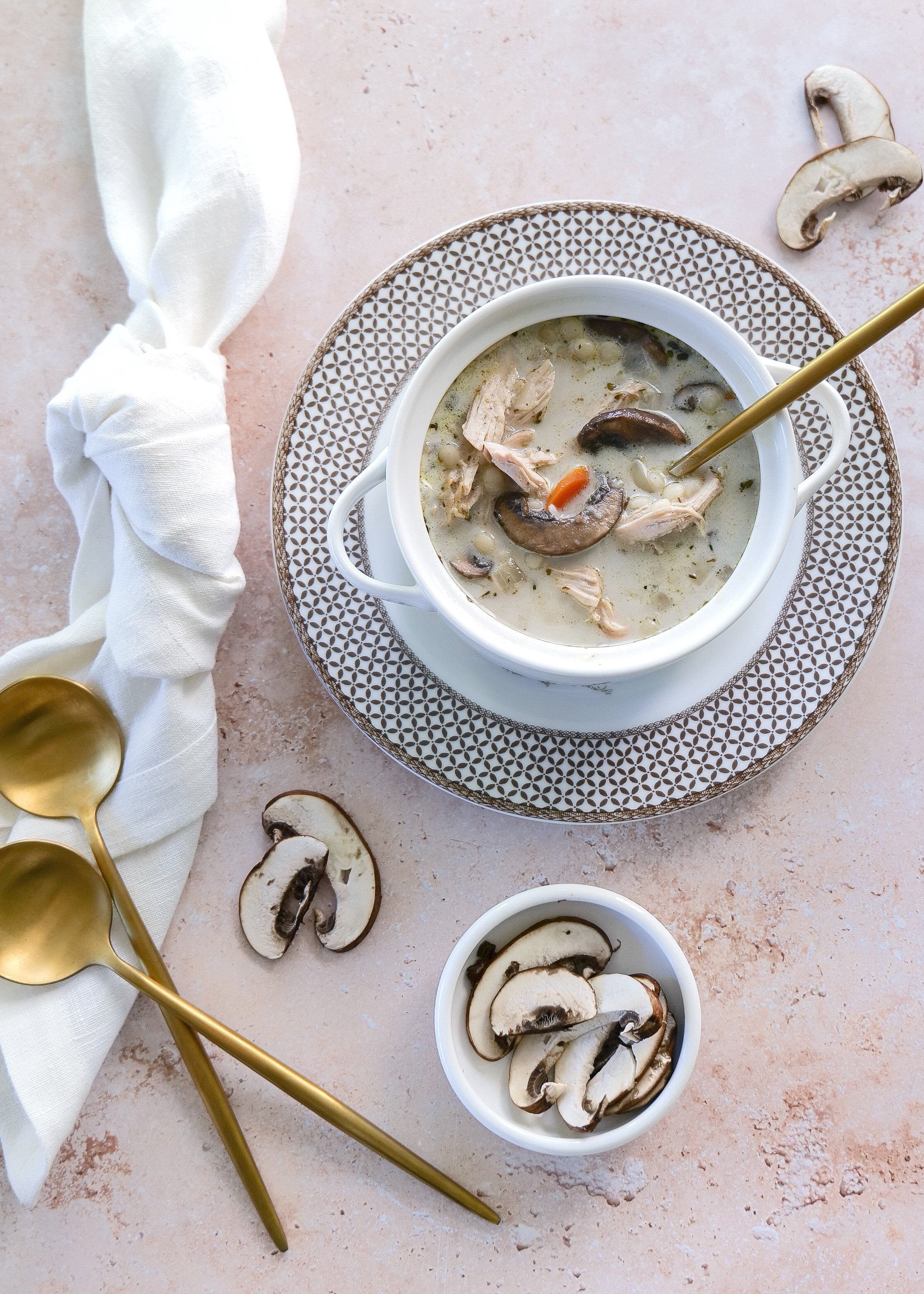 Creamy chicken couscous soup with mushrooms and carrots served warm in a bowl.