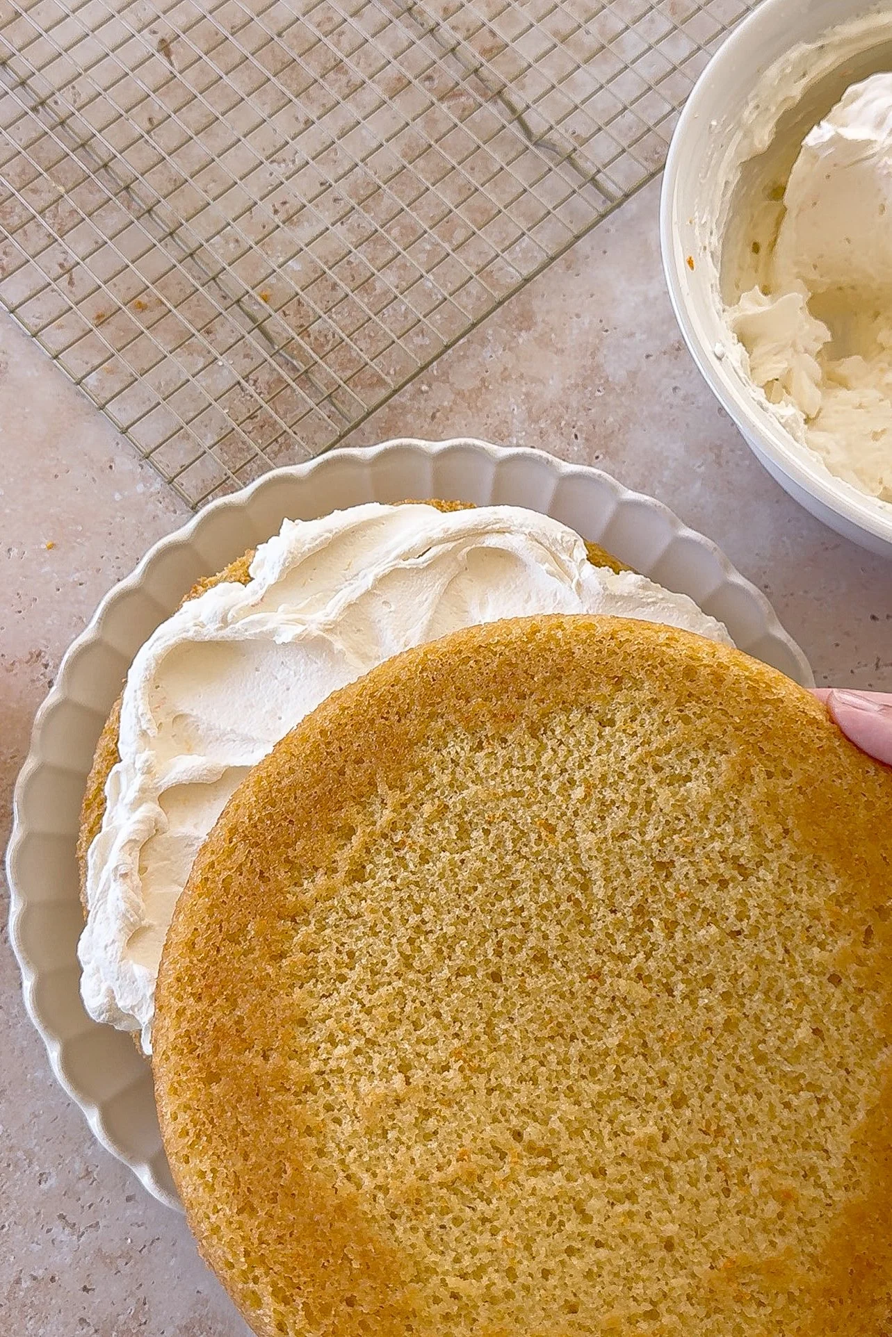 Second orange olive oil cake layer being placed over mascarpone cream