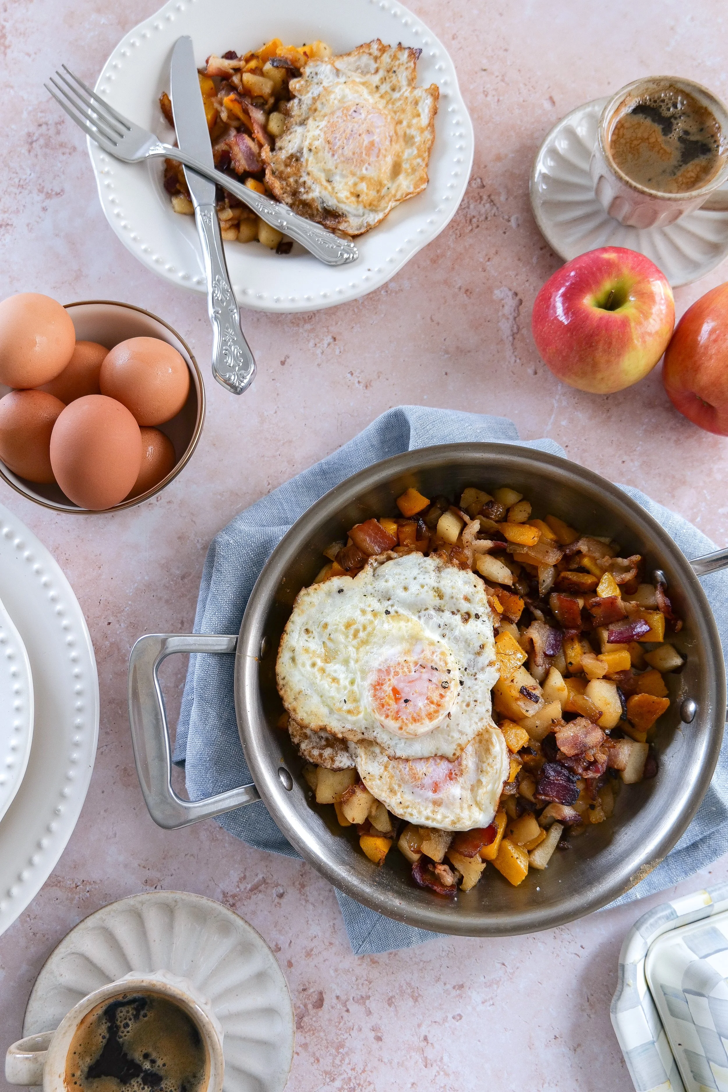 Butternut squash breakfast hash with roasted squash, apples, crispy bacon, onions, and fried eggs.