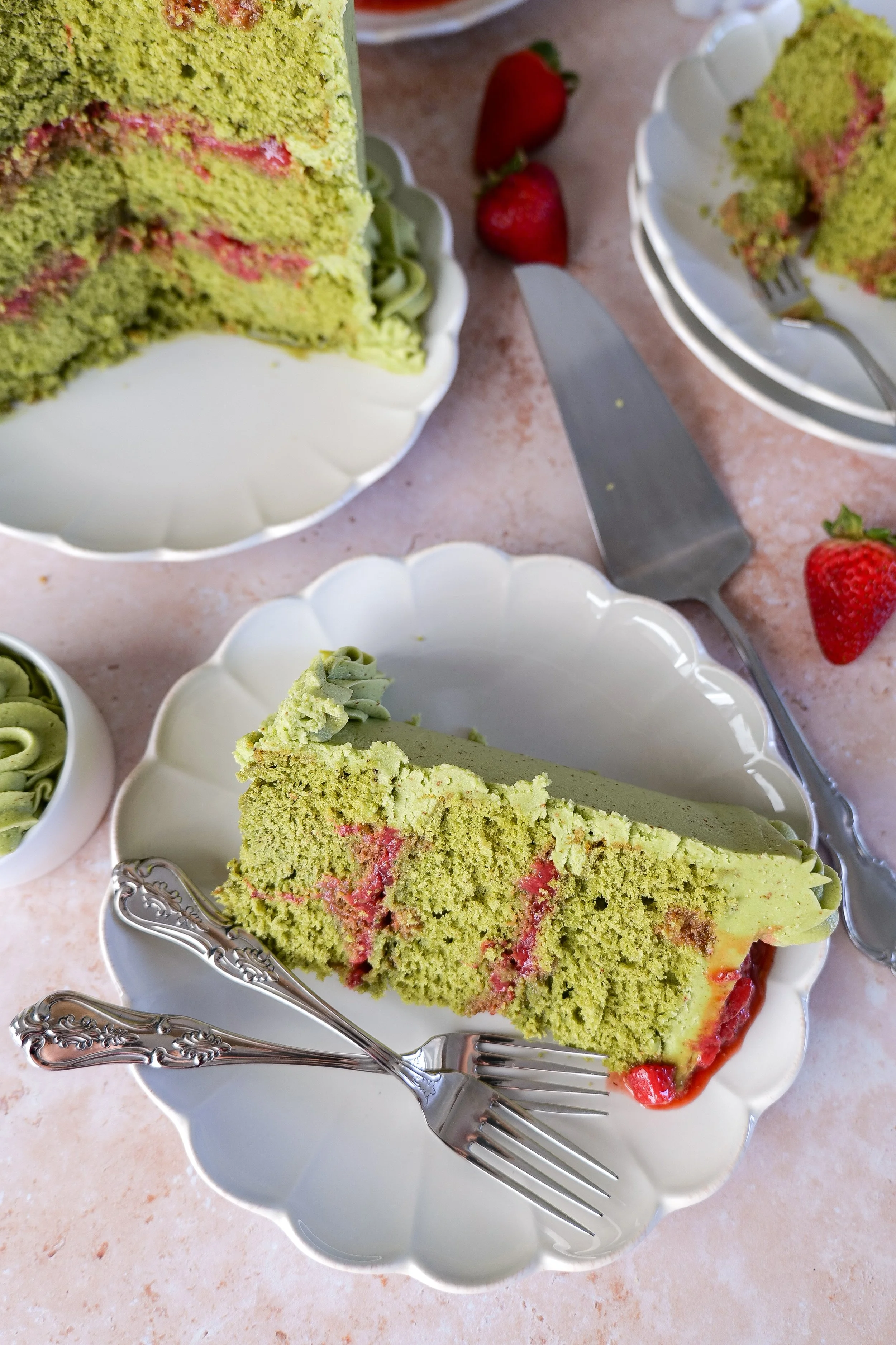Layered matcha strawberry cake slices with fluffy frosting and strawberry filling