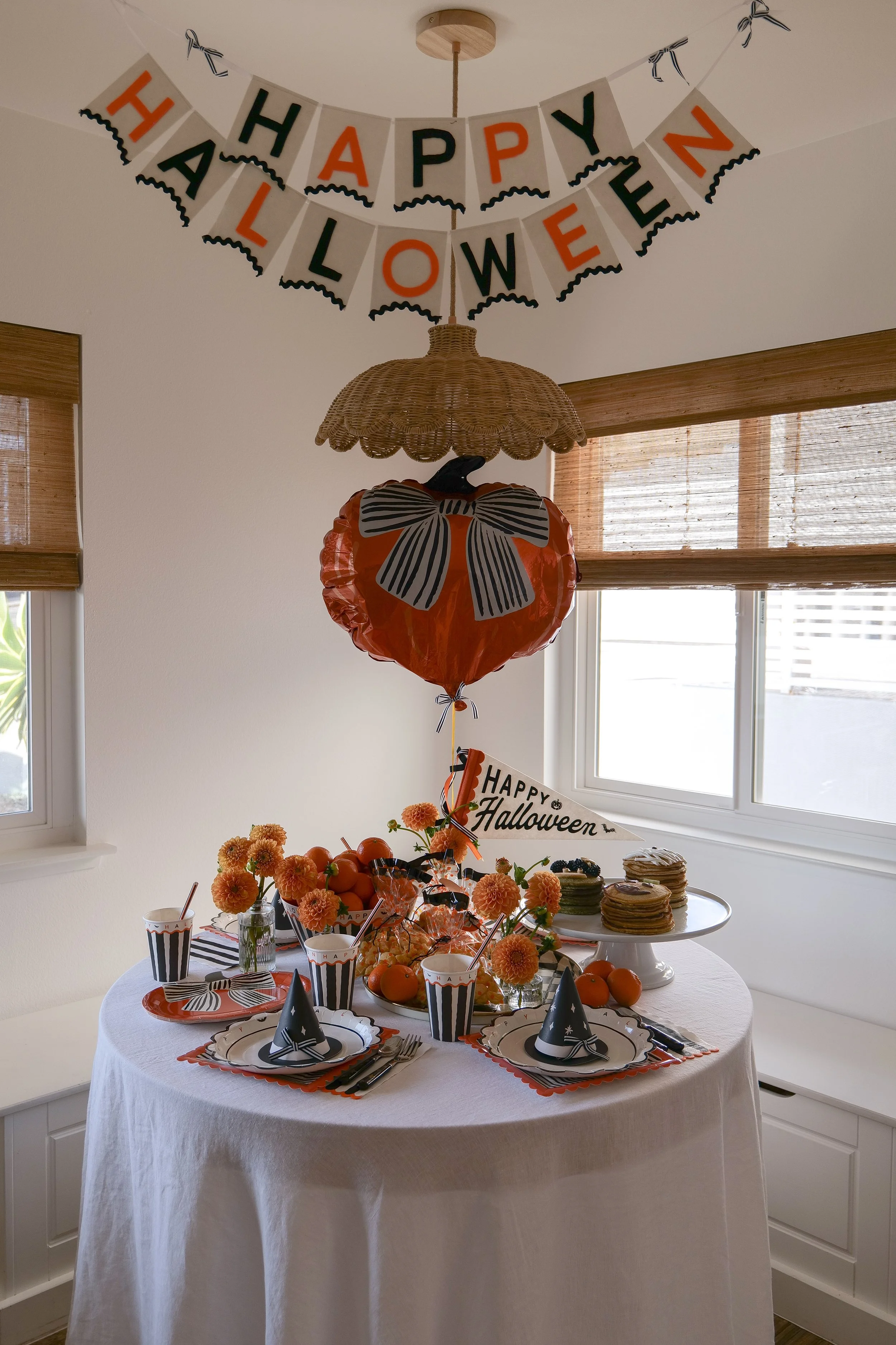 Halloween breakfast table for kids with festive pancakes, orange flowers and Halloween table decorations.