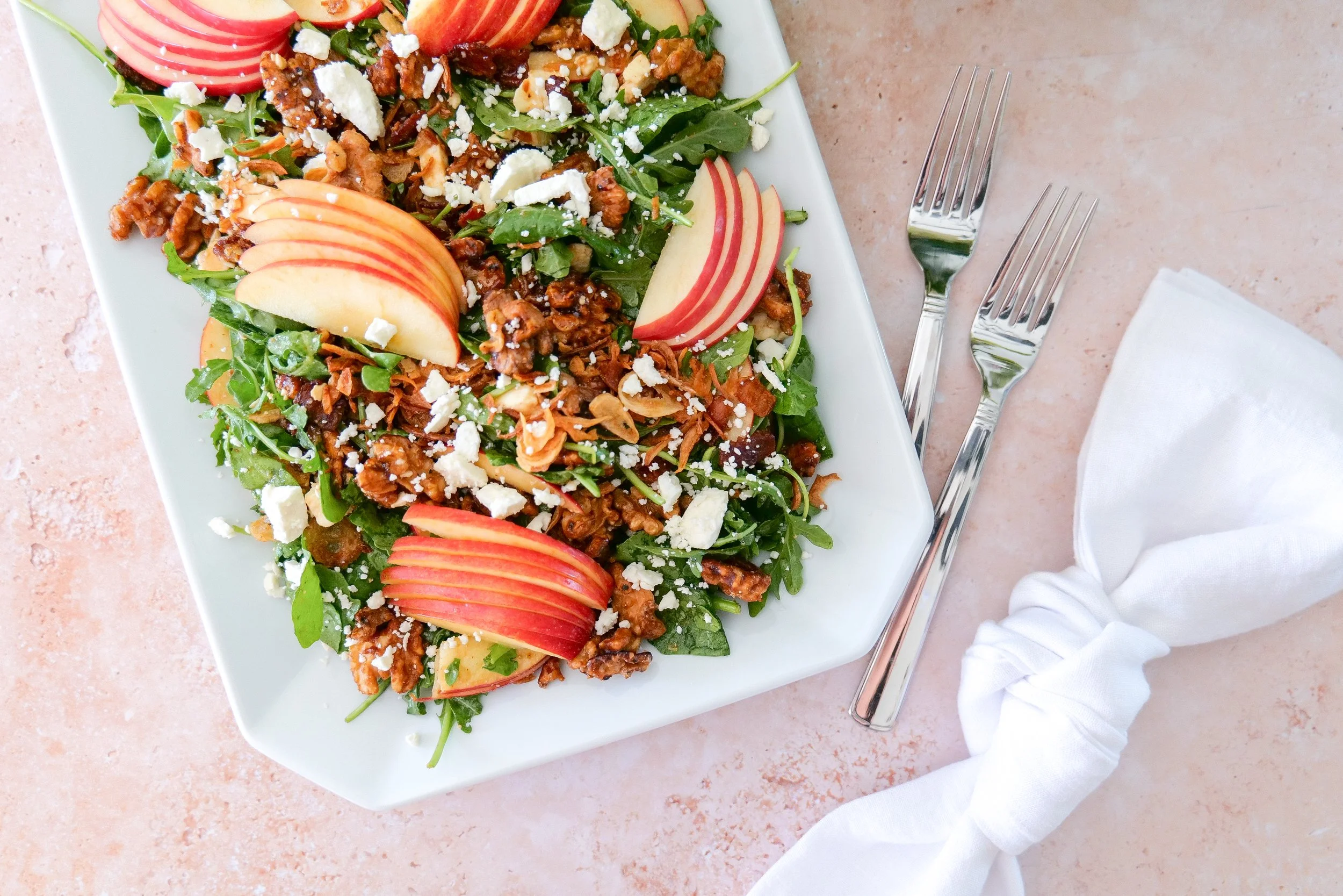 Close-up of maple bacon salad topped with fresh apple slices, feta and crunchy walnuts.