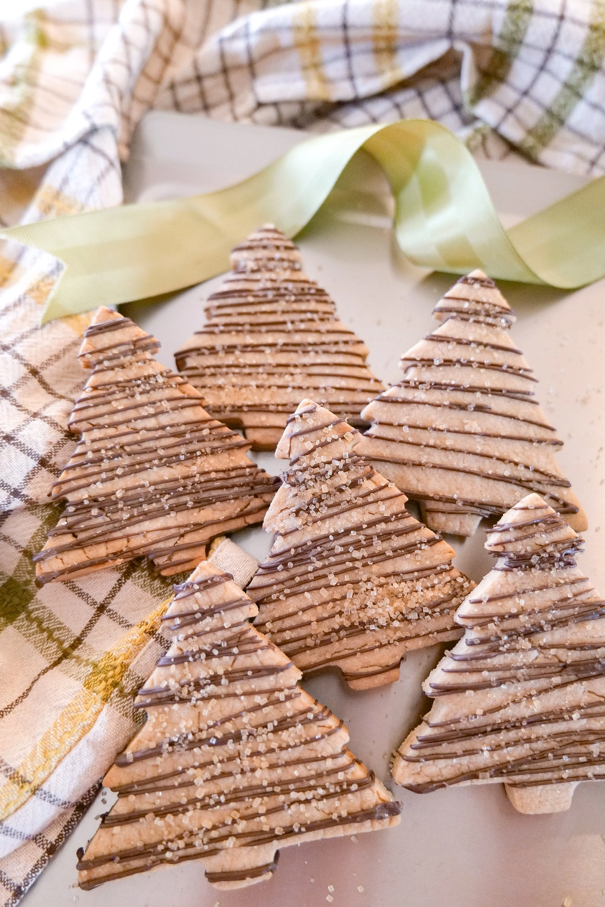Homemade shortbread Christmas cookies finished with thin lines of melted milk chocolate and sparkling sugar.