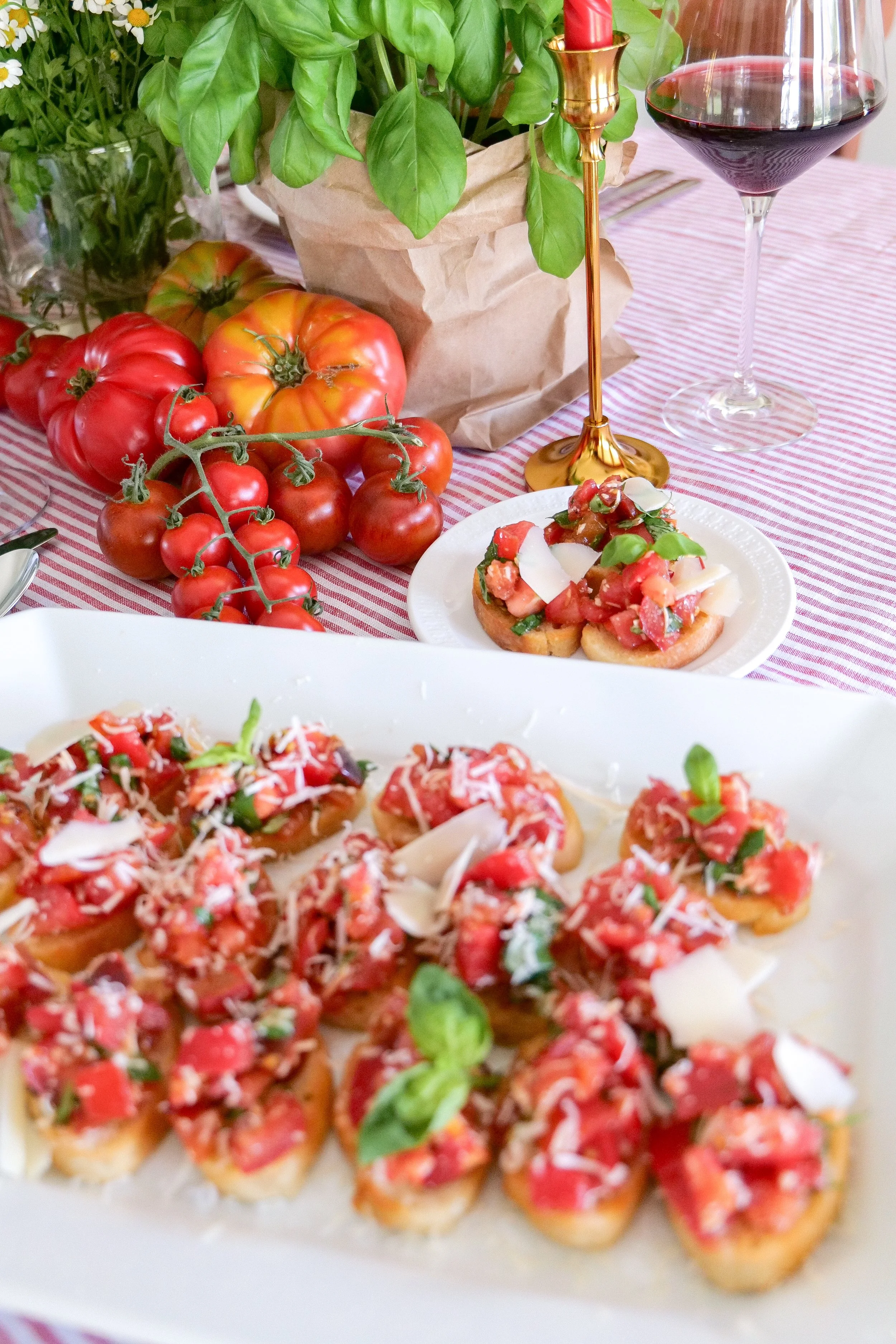 Bruschetta appetizer platter on a summer table with fresh tomatoes, basil and wine