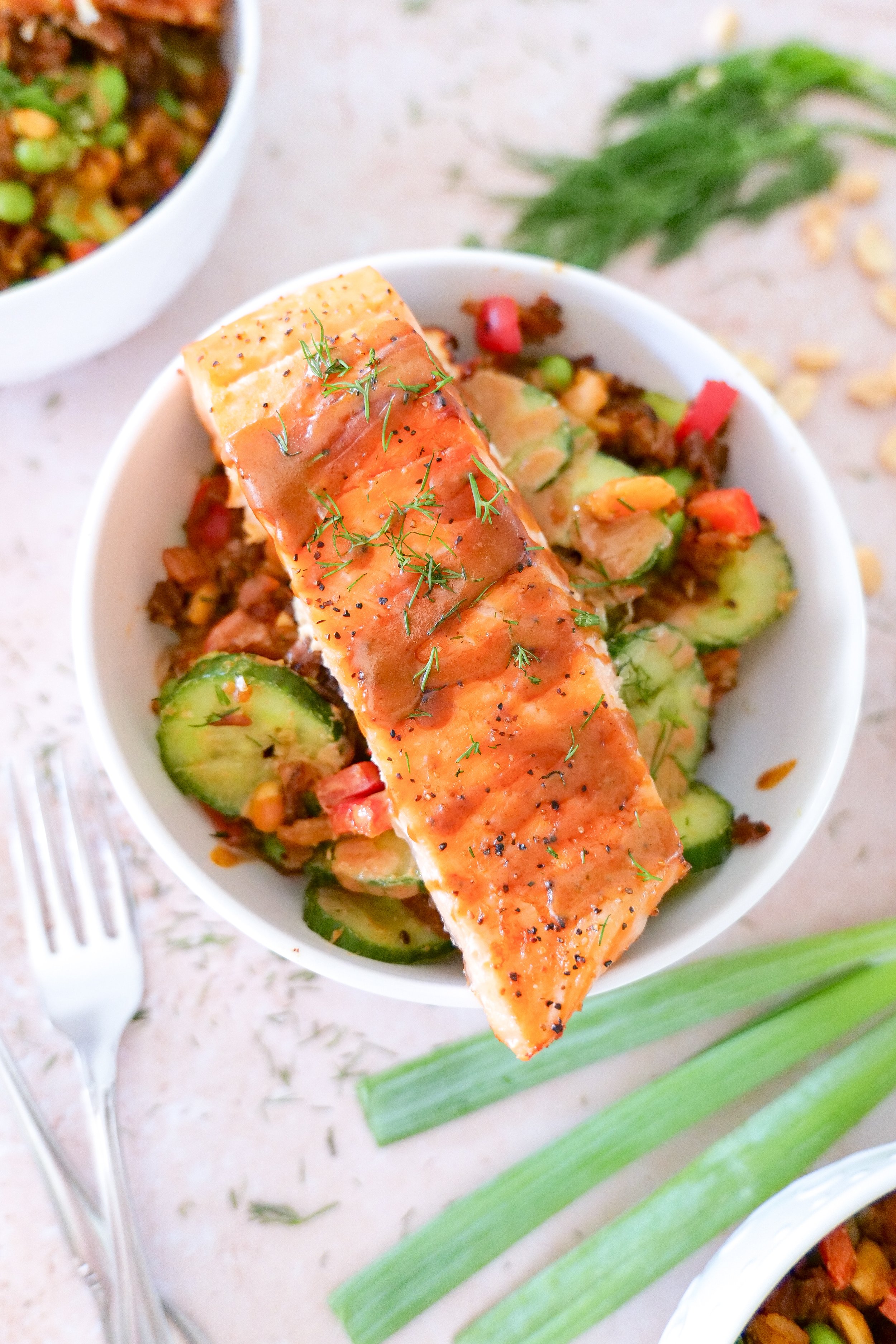 Close-up of crispy rice salad topped with pan-seared salmon and creamy peanut sauce.