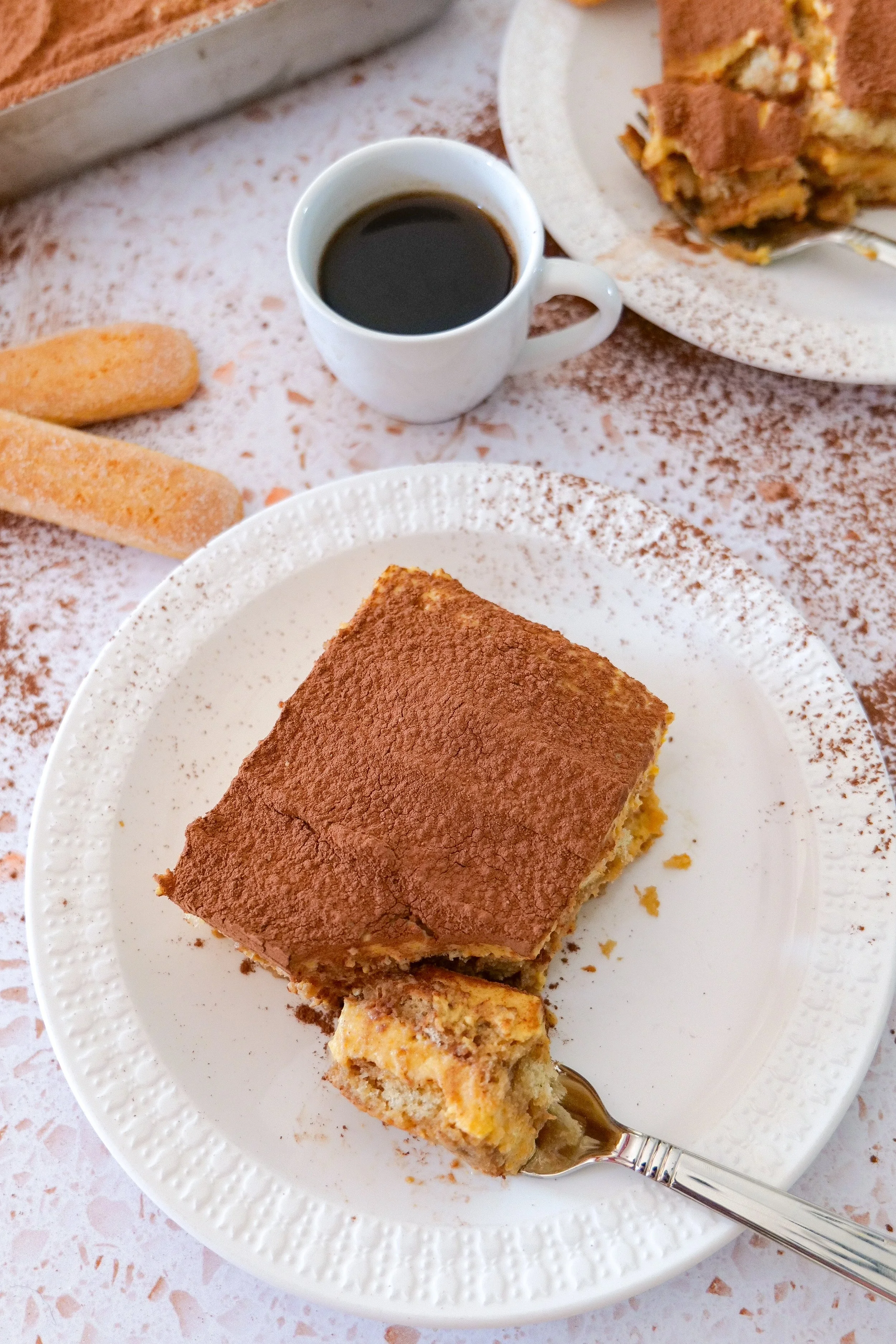 Slice of pumpkin tiramisu with espresso-soaked ladyfingers and creamy pumpkin filling.