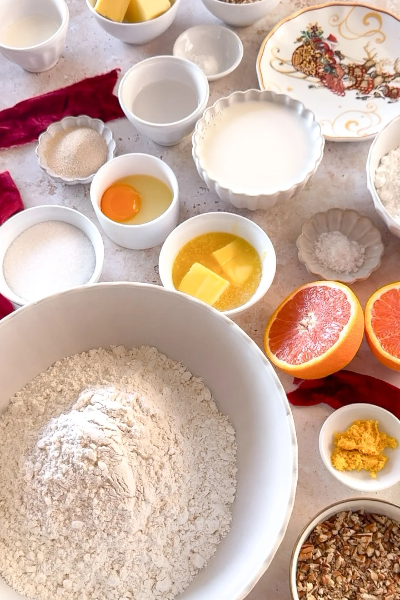Ingredients for homemade orange cinnamon rolls, including flour, butter, cinnamon, oranges, and pecans.