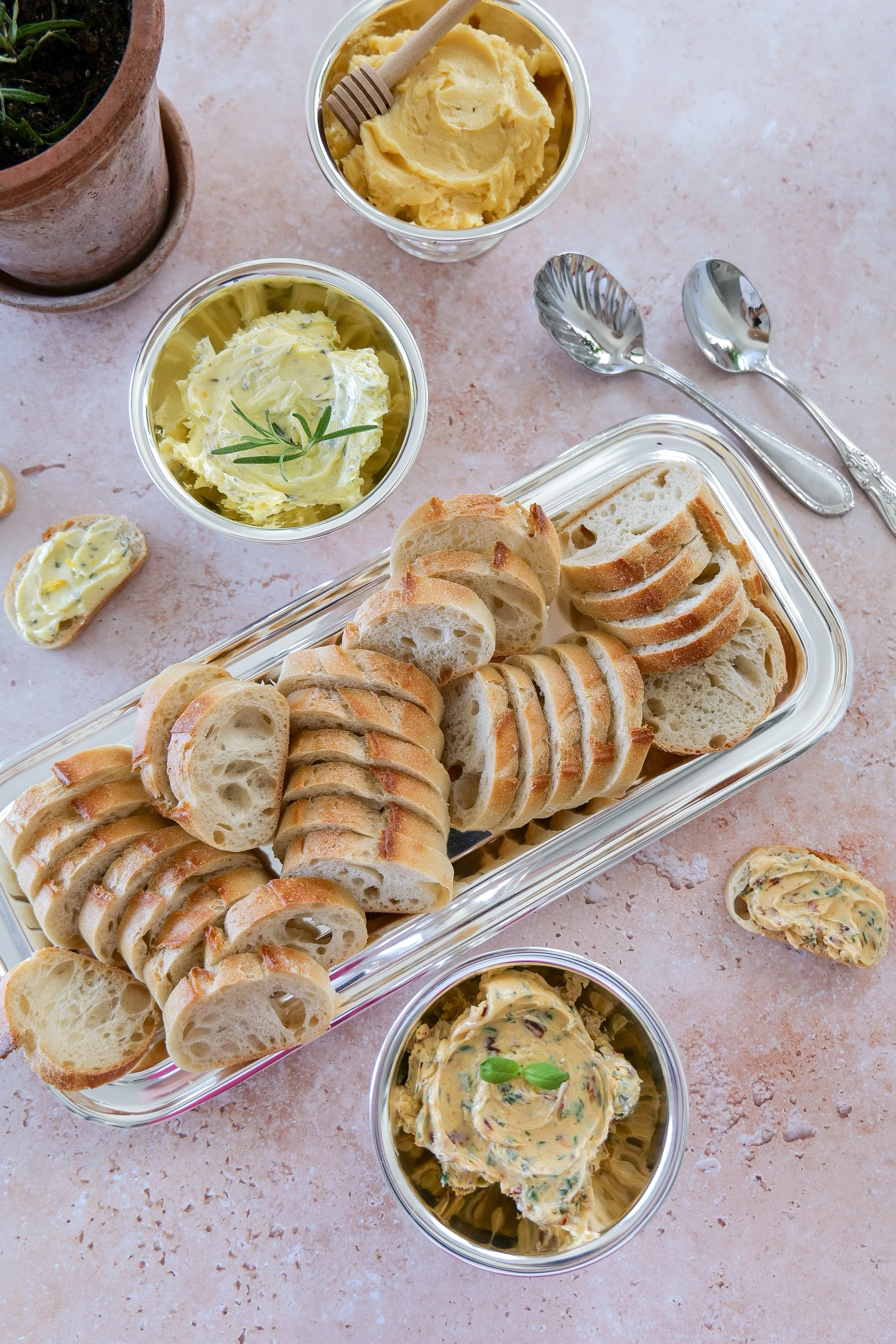 Assorted flavored butter in a metal cup served with sliced toasted baguette