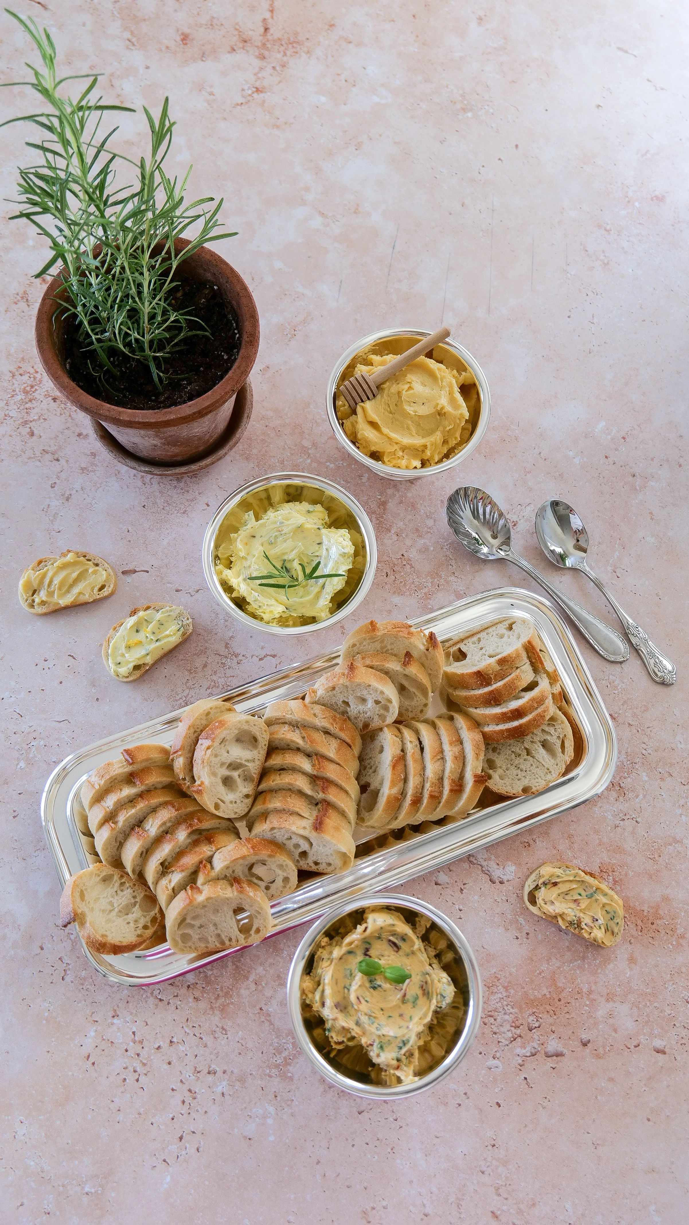 Three compound butter flavors in a metal cup with toasted baguette slices
