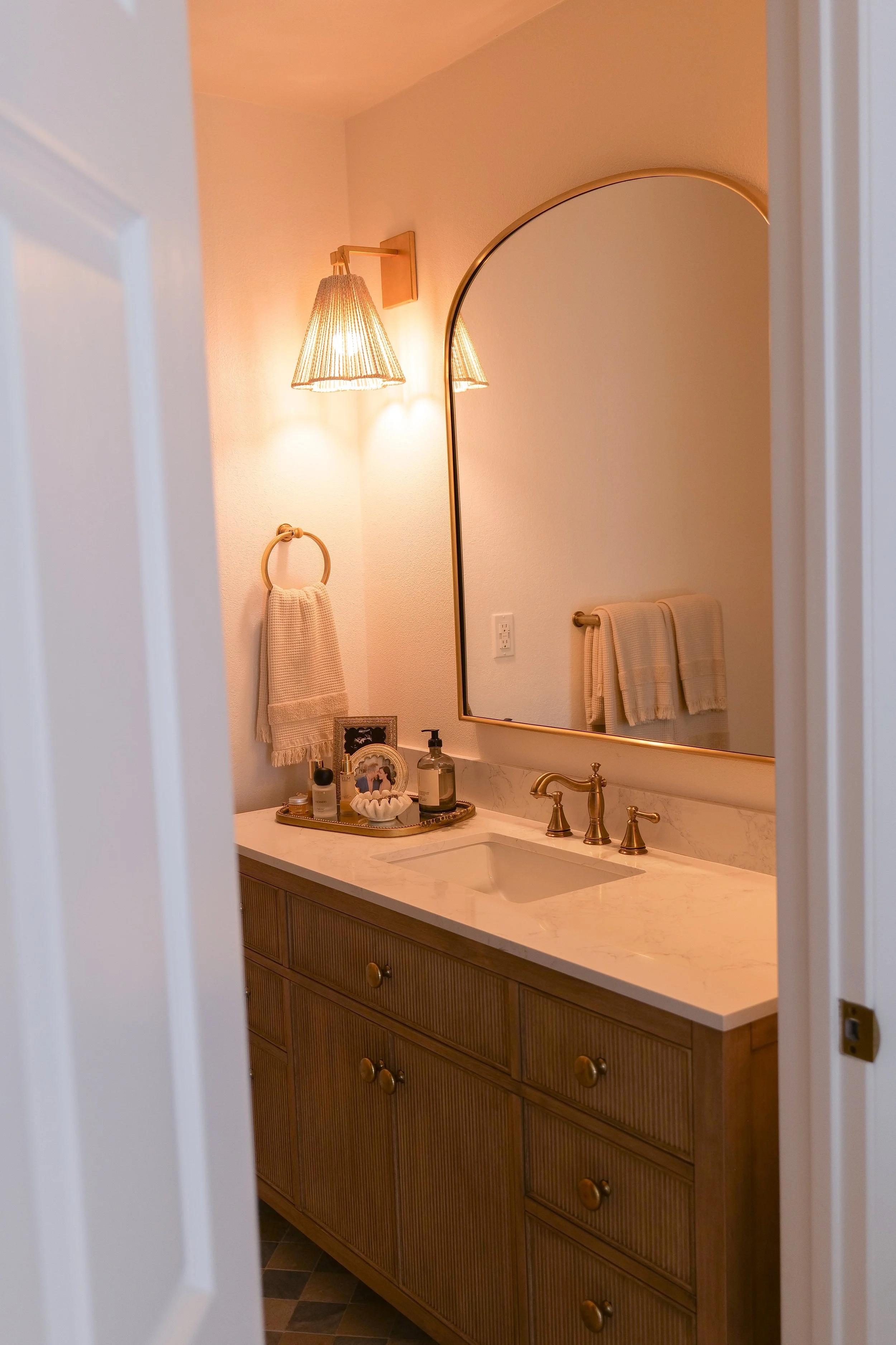 Remodeled coastal bathroom with blue floor tile, a warm-toned vanity, white walls, and a glass shower door.