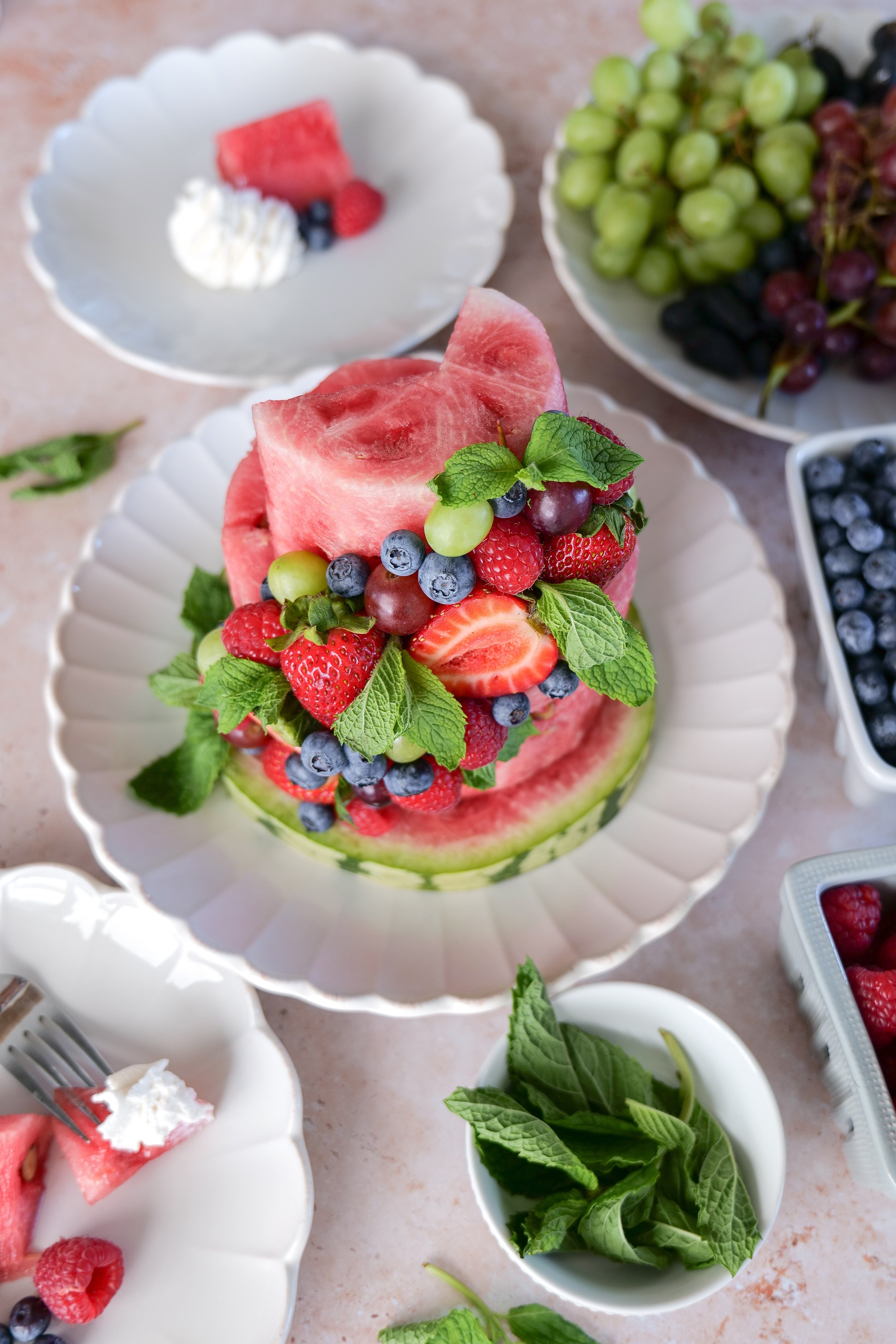 Sliced watermelon fruit cake served chilled with homemade whipped cream on the side.