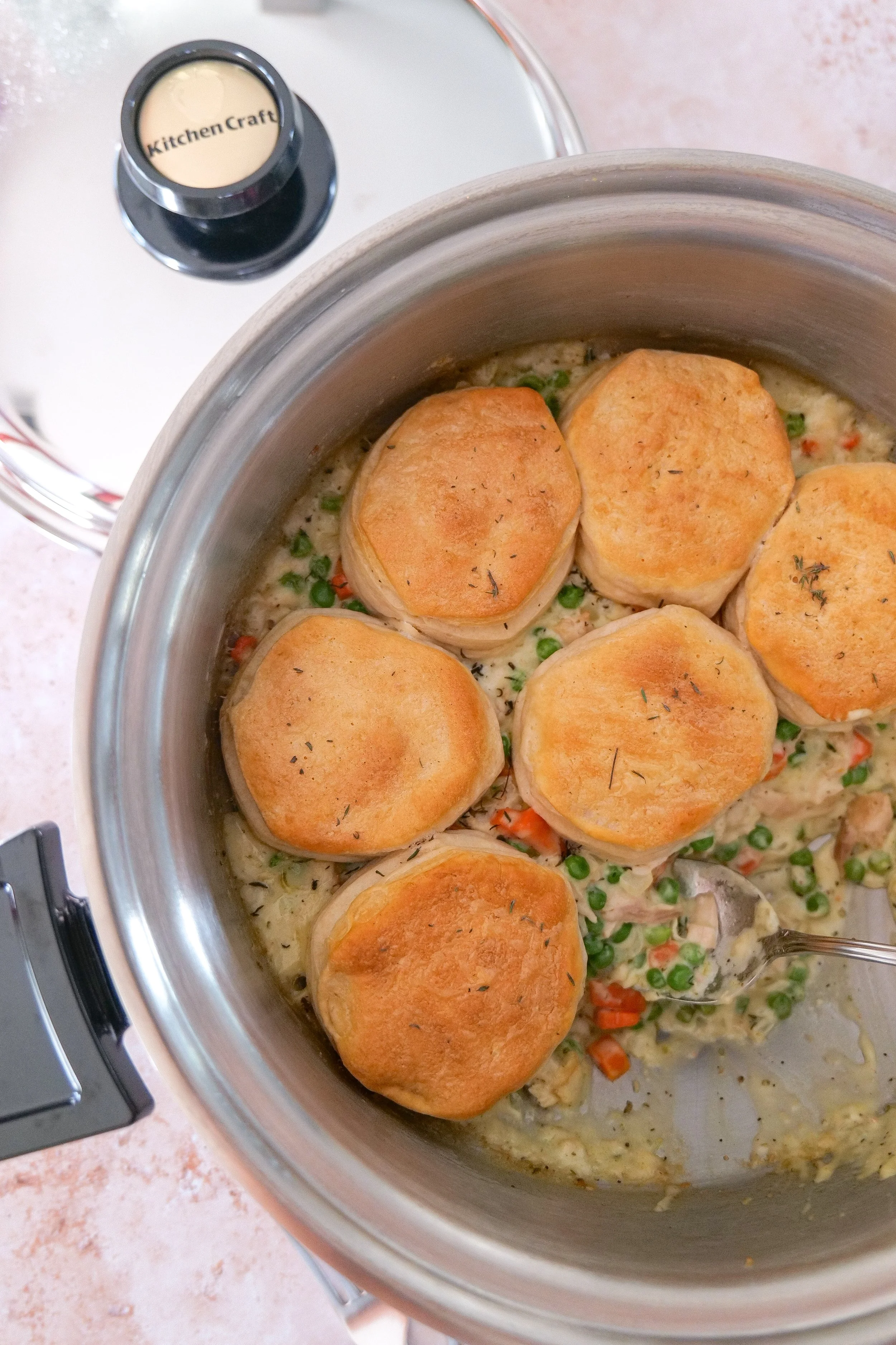 Creamy homemade chicken pot pie filling with tender chicken, carrots, peas, garlic, and herbs simmering in a skillet.