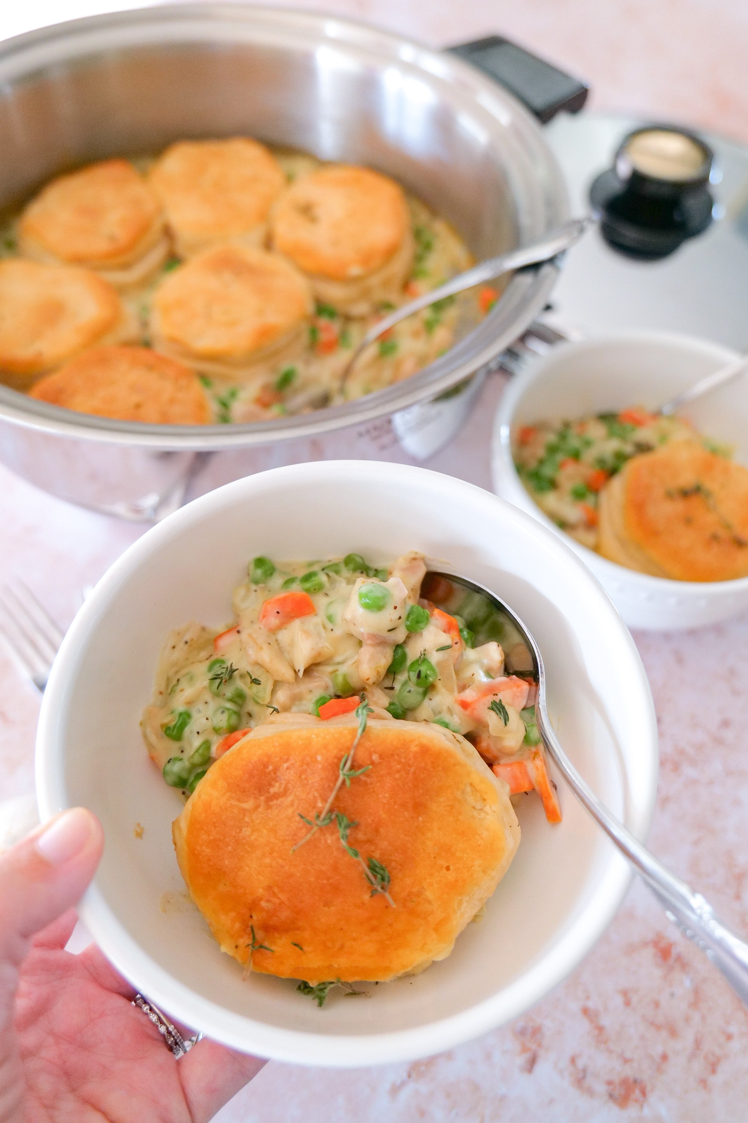 Flaky refrigerated biscuits arranged on top of creamy chicken pot pie filling before baking.