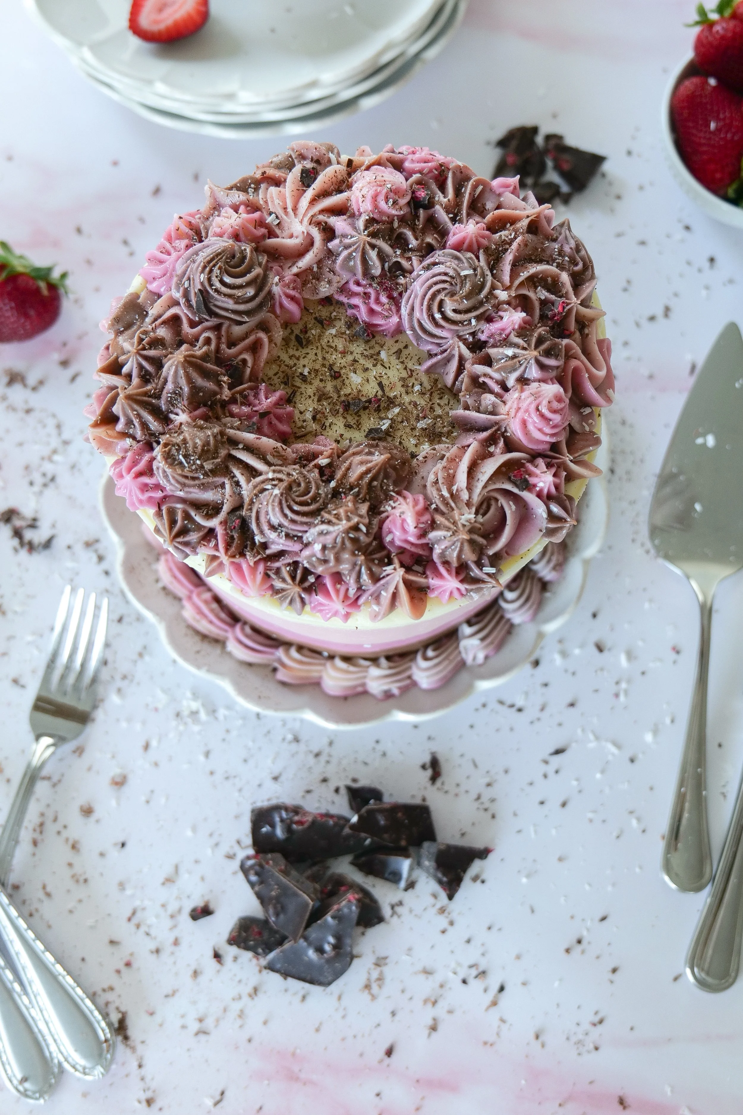 Decorated Neapolitan cake with chocolate, strawberry, and vanilla layers, topped with frosting and sprinkles.