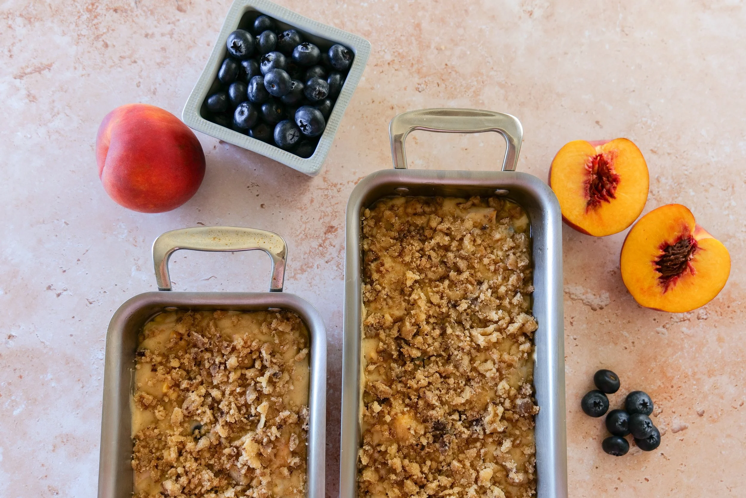 Blueberry Peach Bread batter topped with cinnamon streusel in a loaf pan before baking.
