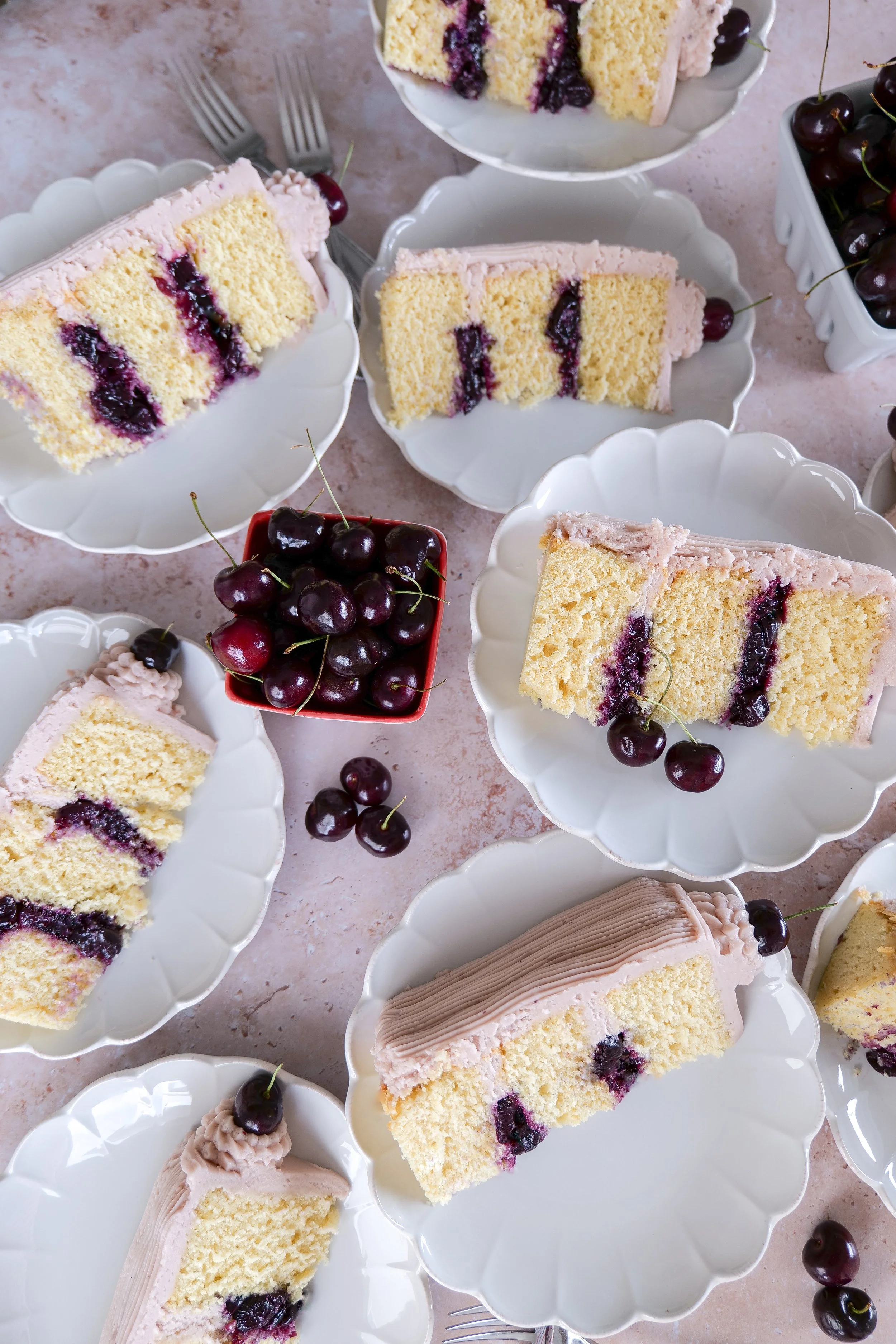 Cross section of vanilla bean cherry layer cake showing thick cherry filling between cake layers.
