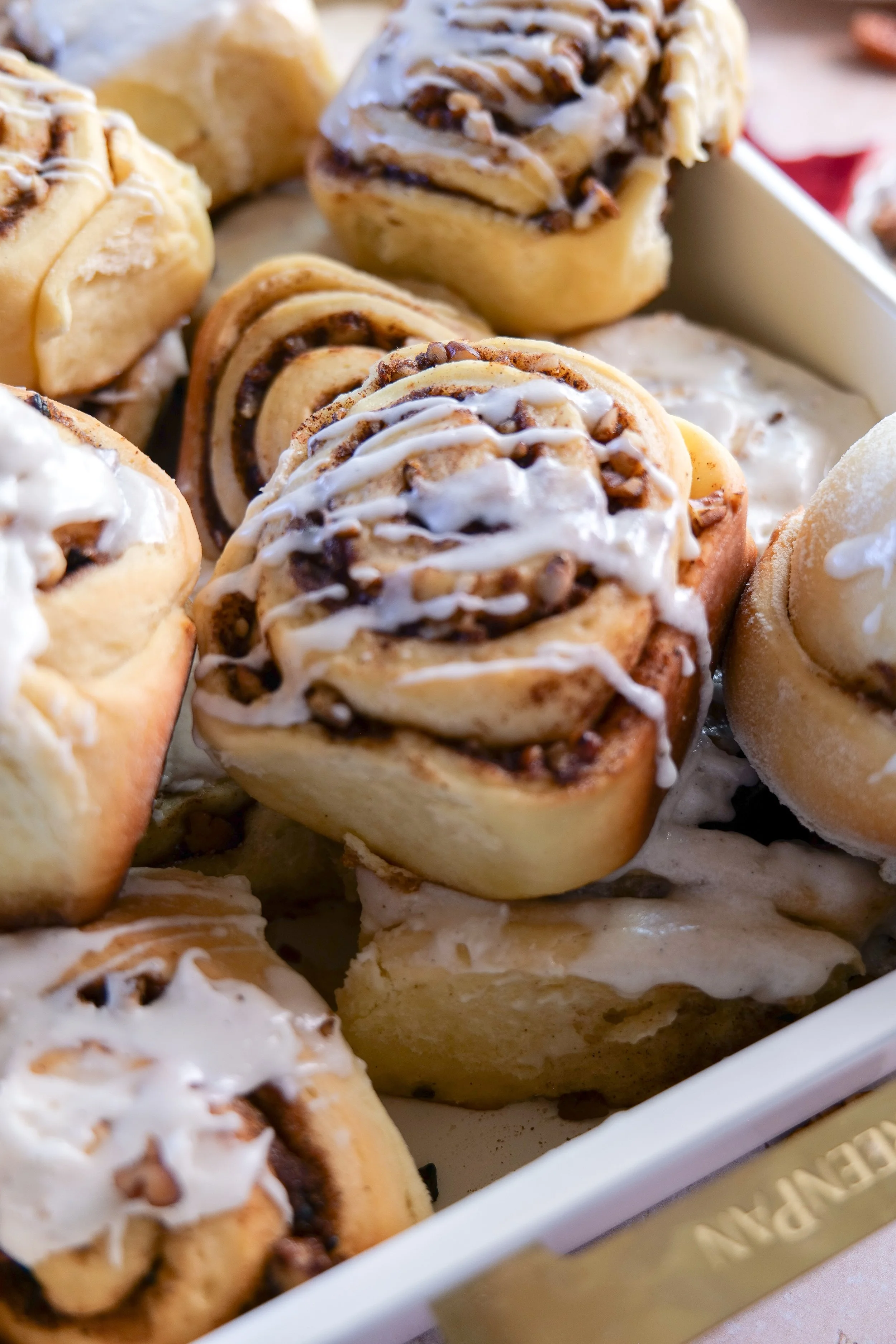 Freshly baked brown butter orange pecan cinnamon rolls topped with vanilla bean glaze.