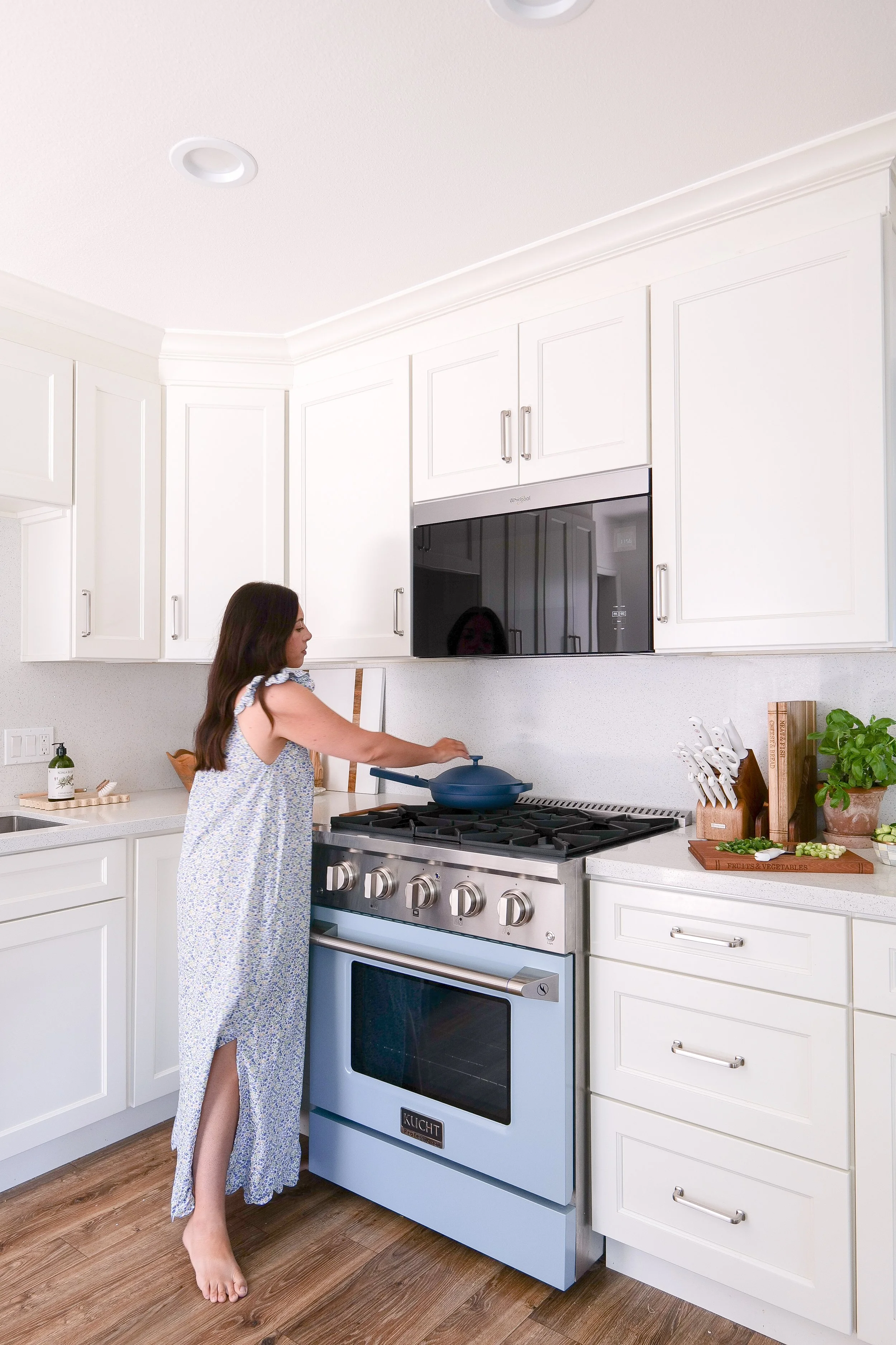 Woman cooking on a light blue range in a timeless coastal kitchen makeover