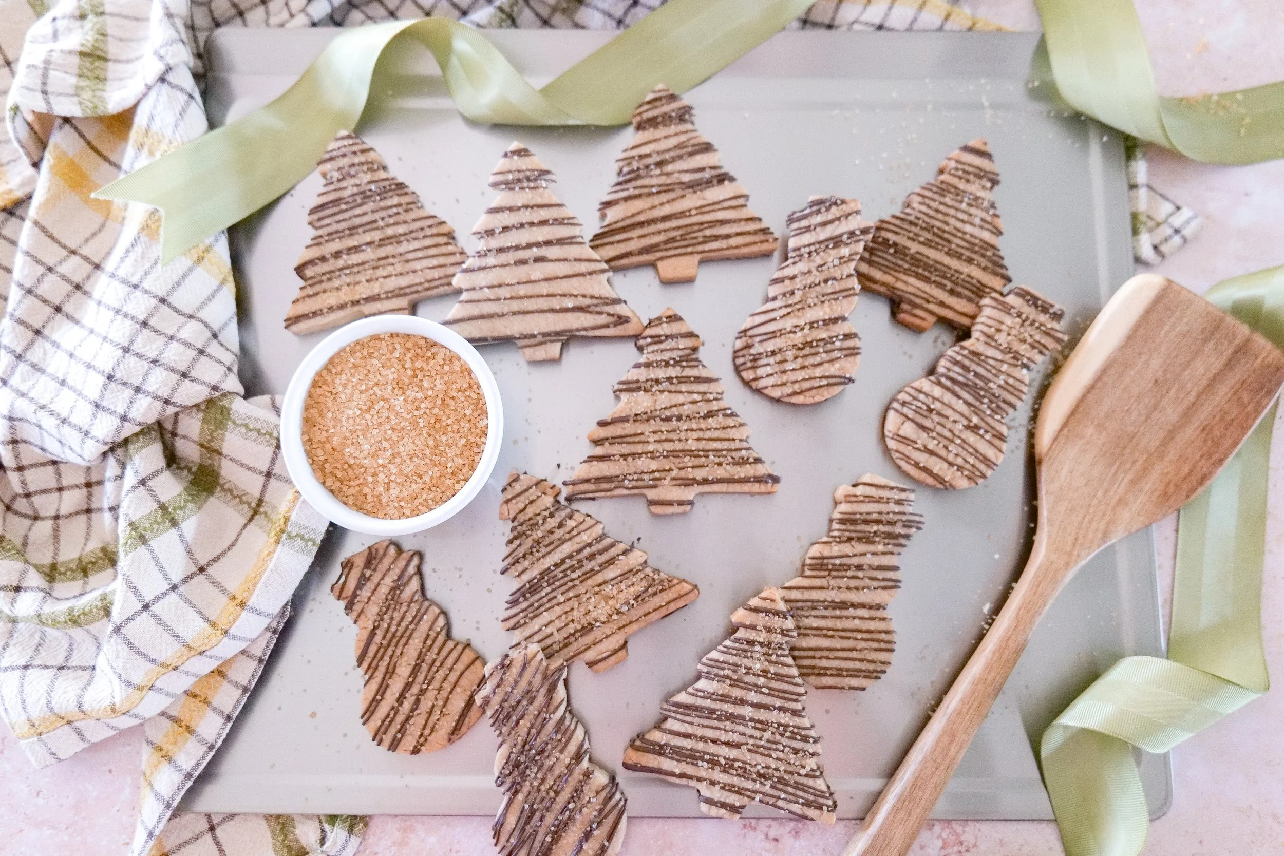 Christmas tree shaped brown butter shortbread cookies decorated with a milk chocolate drizzle and coarse sugar.