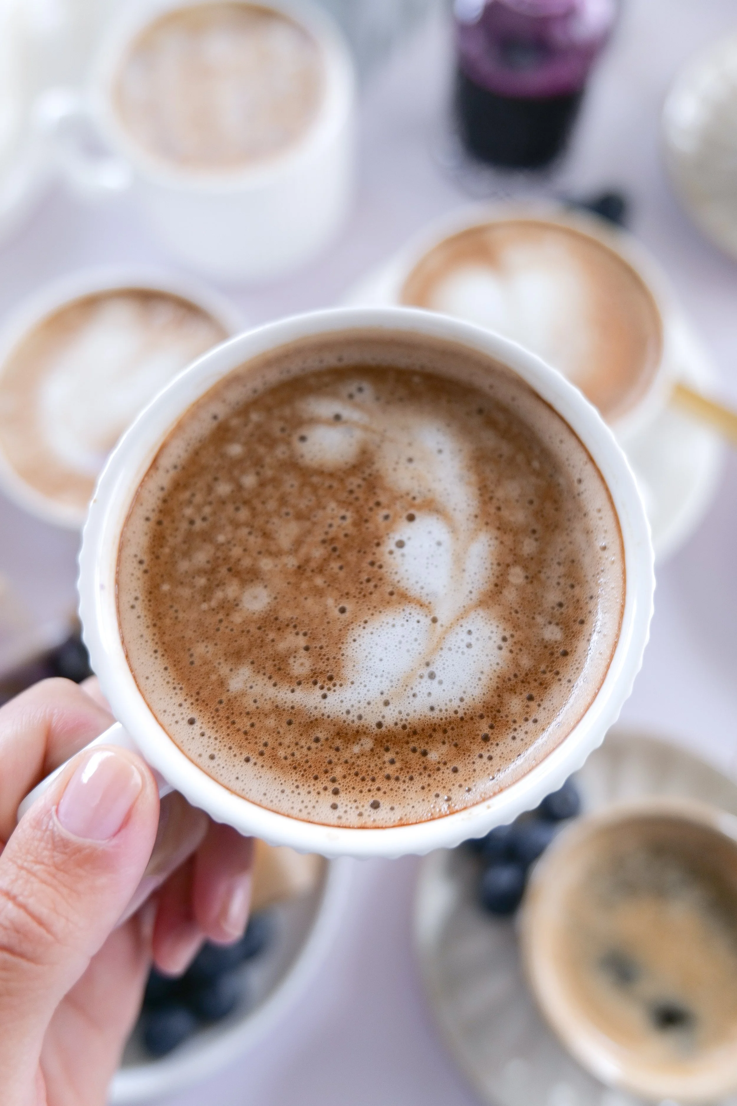 Homemade Blueberry Muffin Latte with heart-shaped latte art and fresh blueberries on the table.