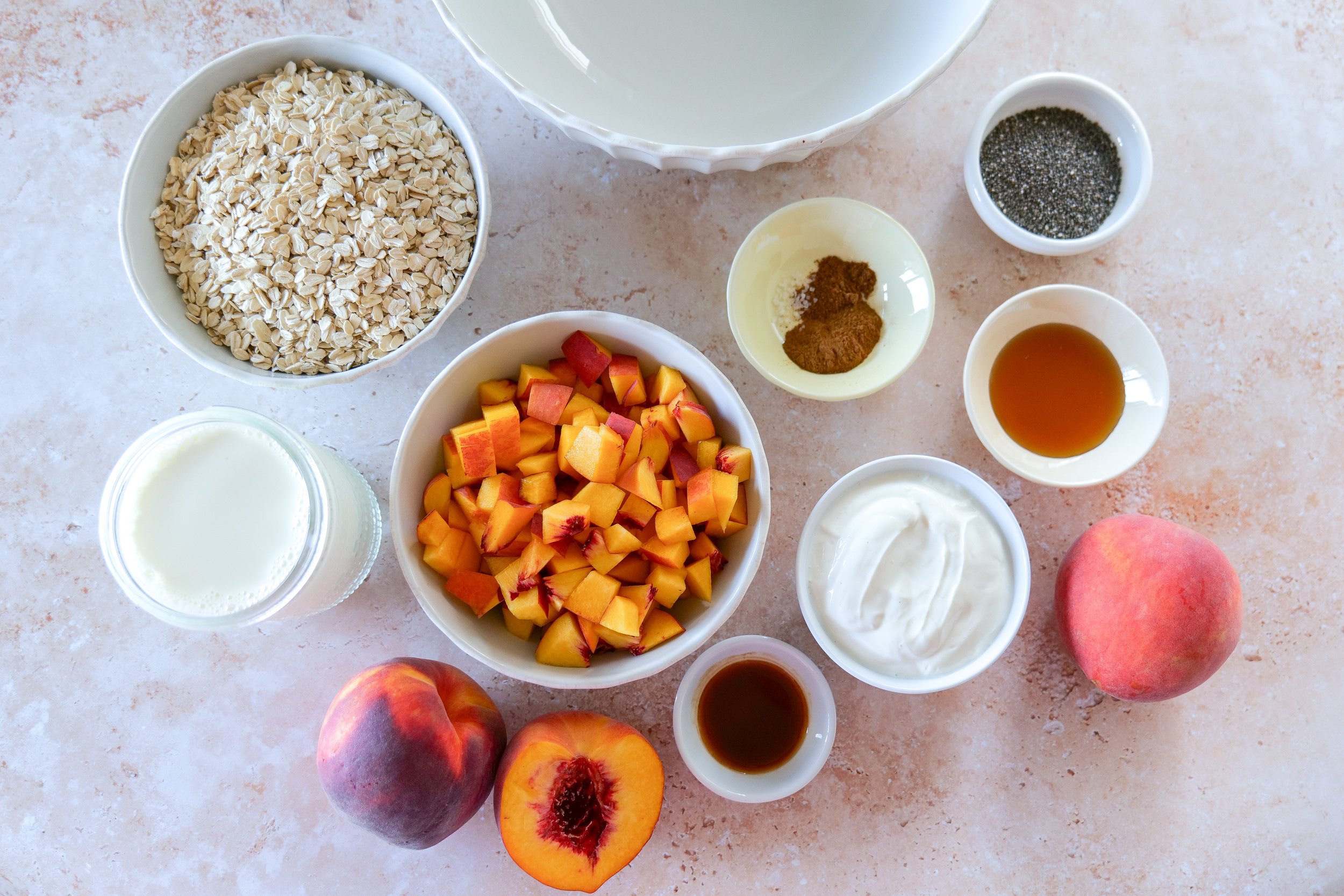Ingredients for Peach Cobbler Overnight Oats including peaches, oats, Greek yogurt, milk, chia seeds, cinnamon, and vanilla.