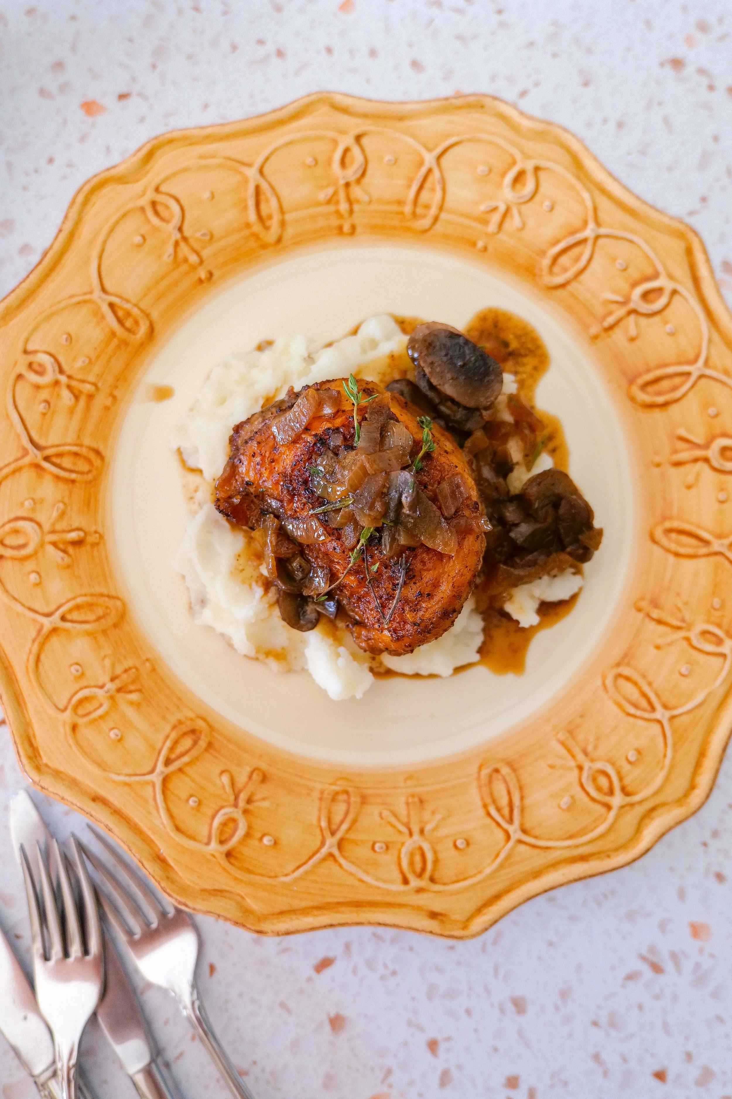 Golden skillet chicken thighs served with sautéed brown mushrooms and caramelized onions.