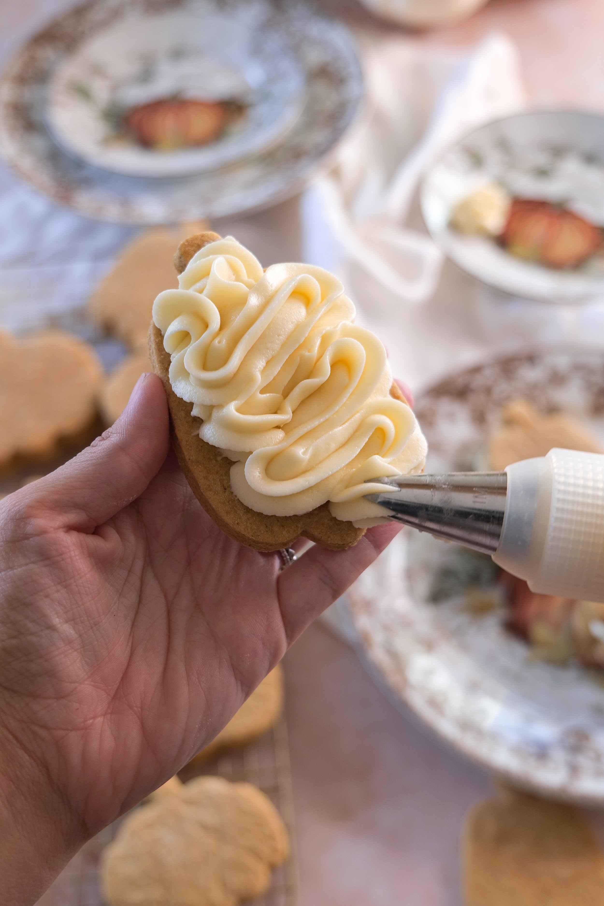 Cream cheese filling being piped onto a pumpkin-shaped cookie