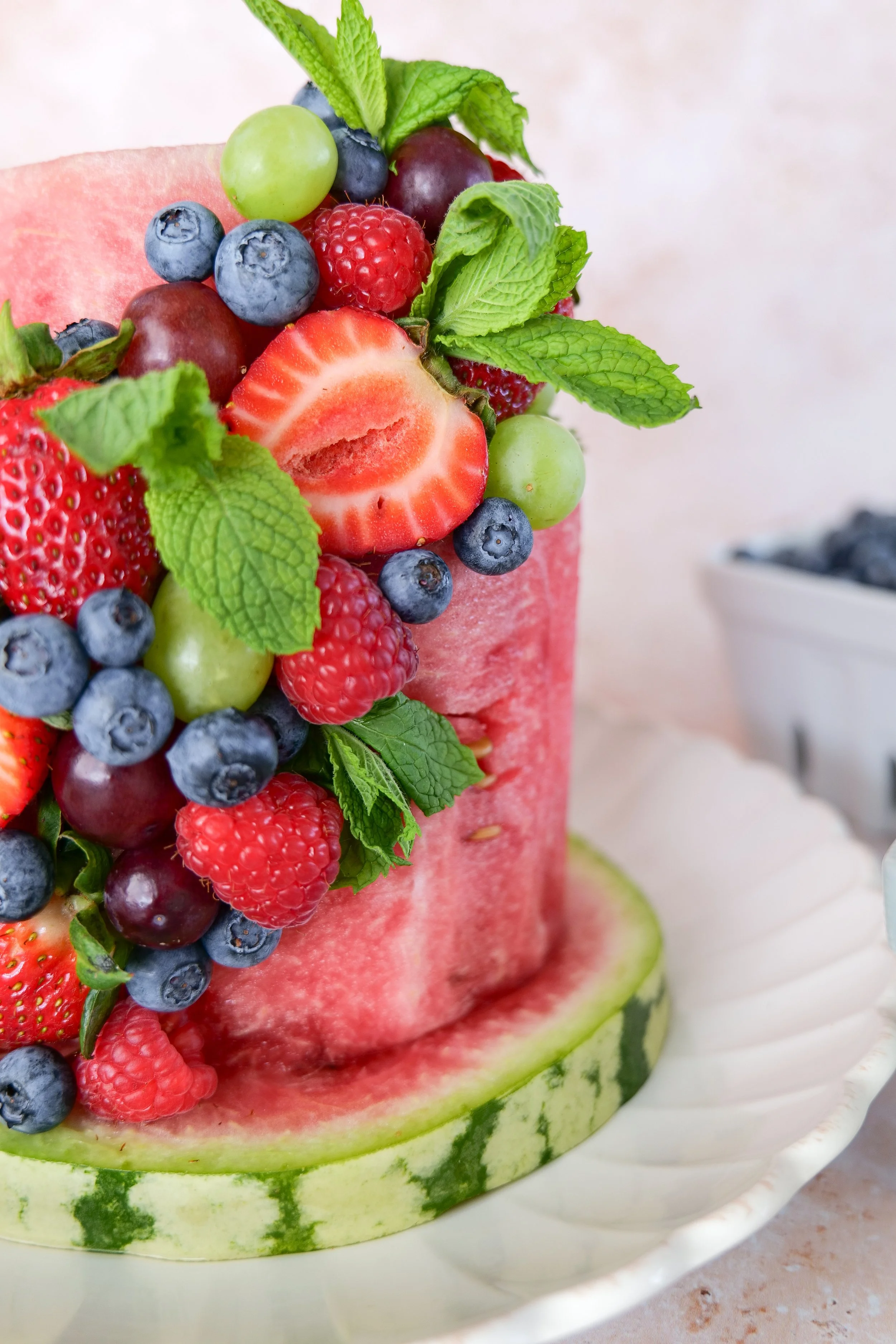 Finished watermelon cake garnished with fresh mint and colorful summer berries and grapes.