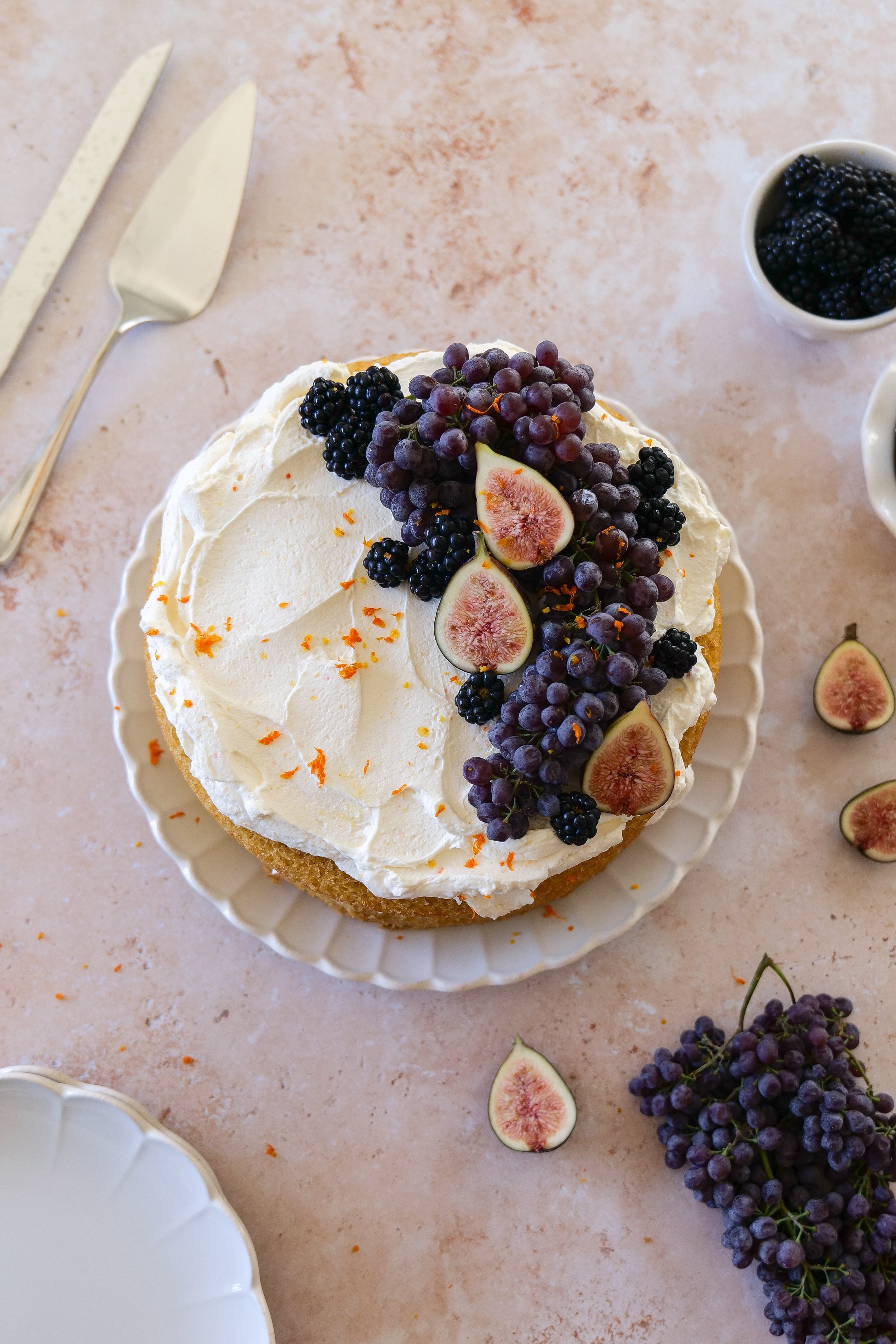 Overhead view of orange olive oil cake topped with mascarpone cream and fresh fall fruit