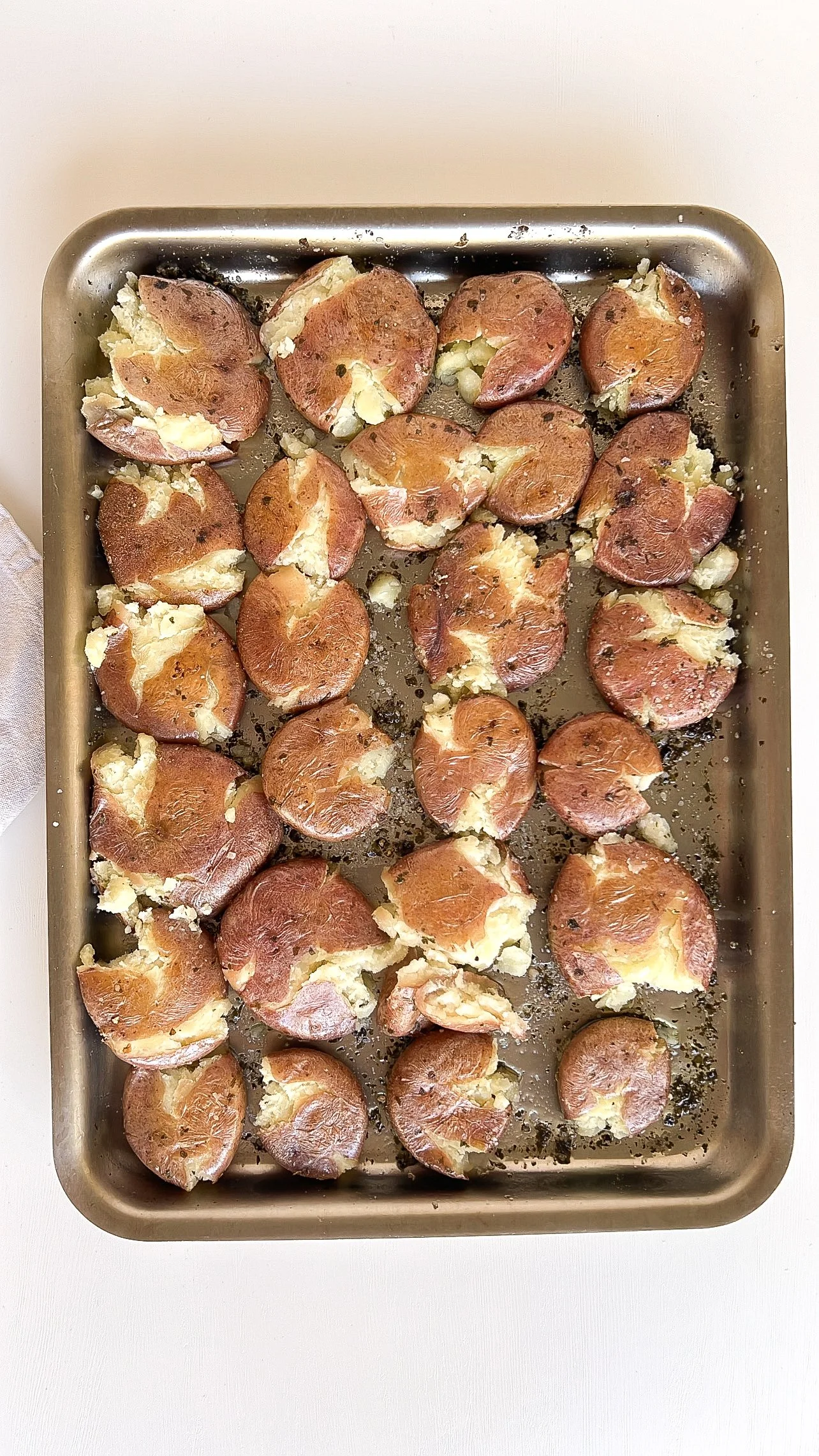 Smashed red potatoes roasting on a baking sheet until crispy
