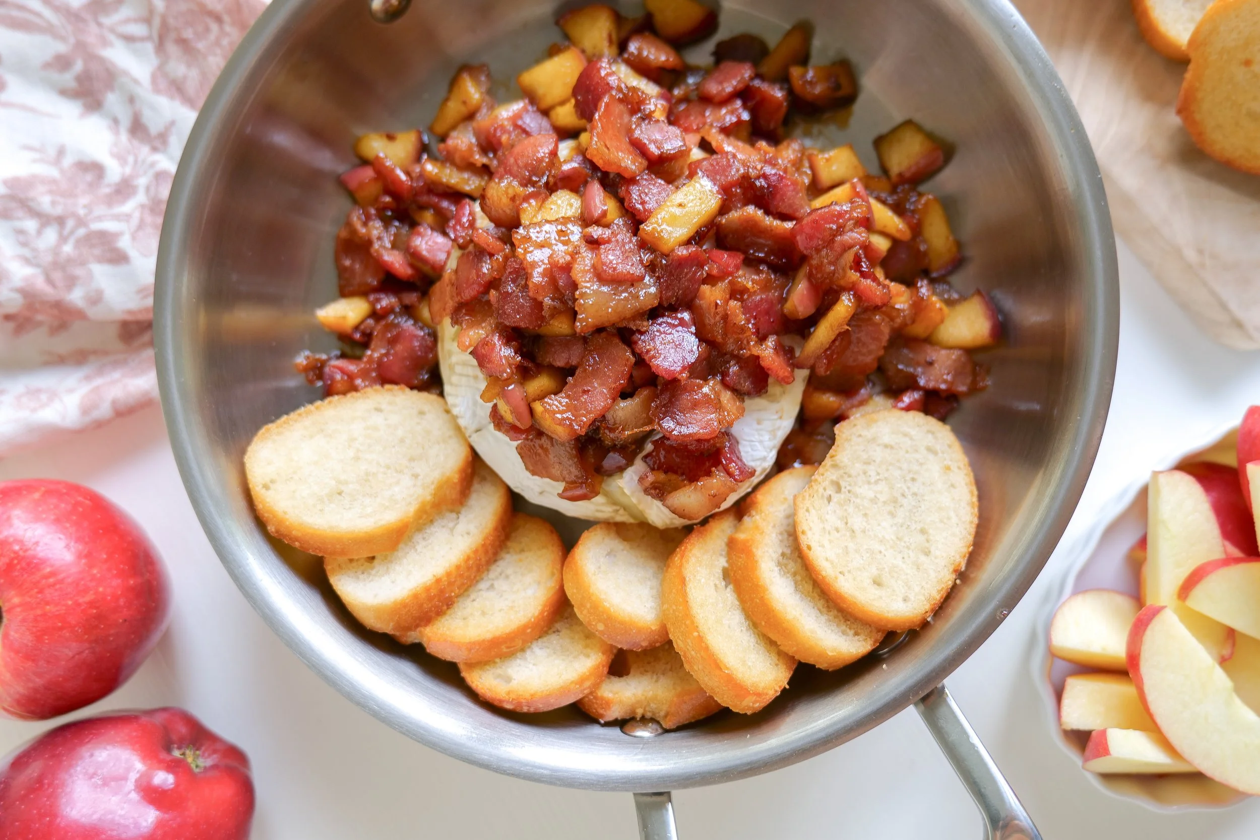 Bacon apple baked brie served as part of a fall cheese board with crackers.