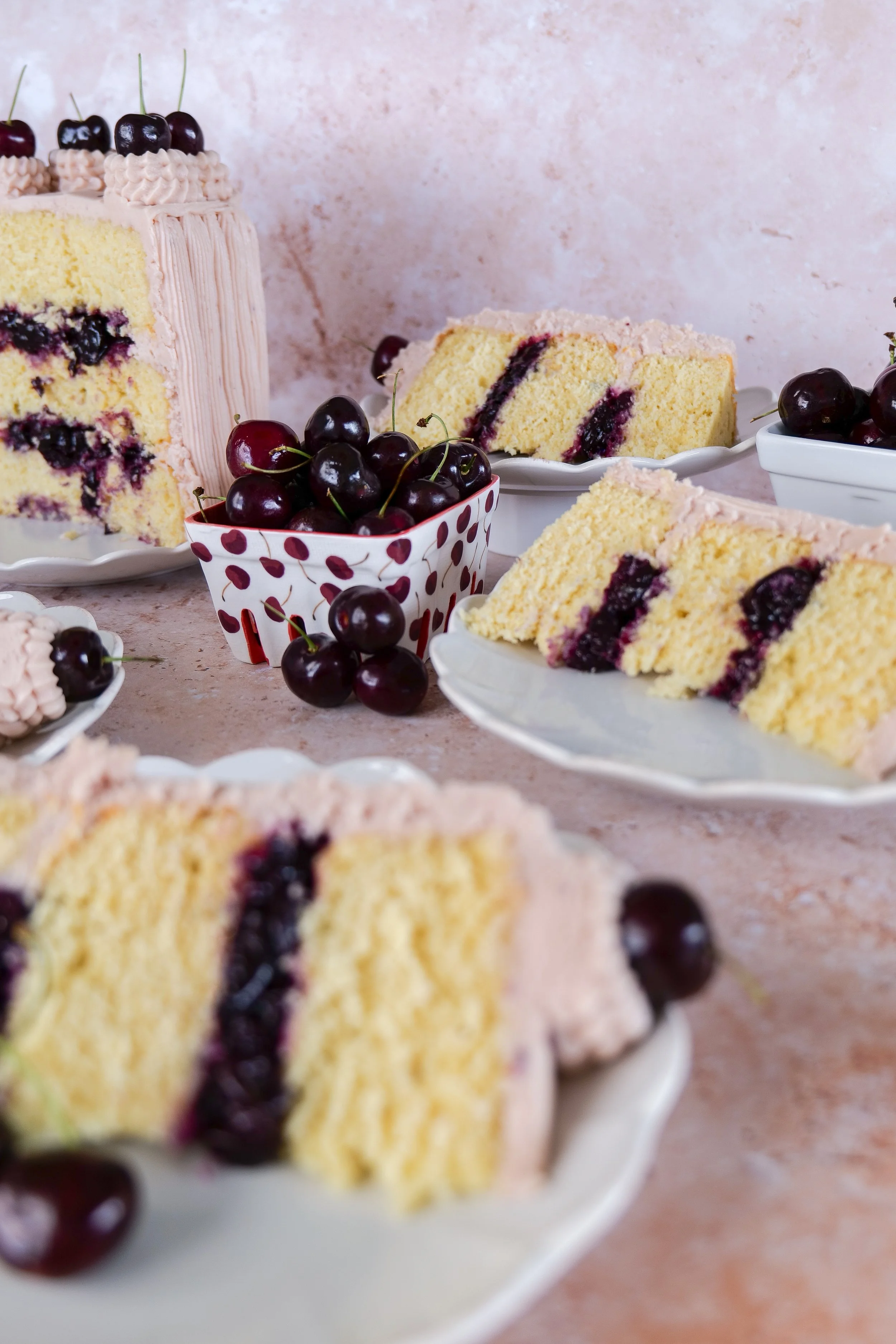 Slice of cherry layer cake served on a white scalloped dessert plate.
