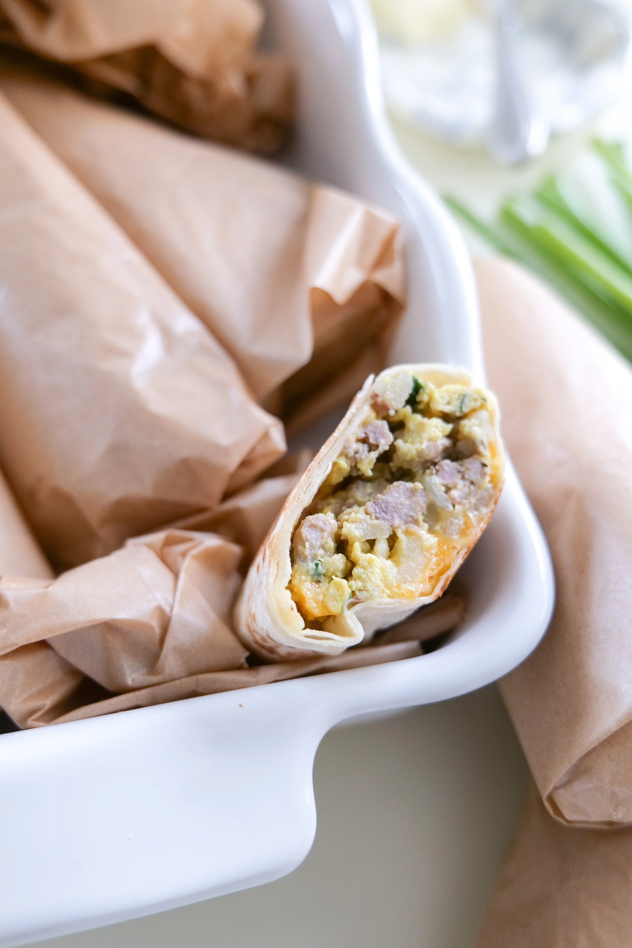 Sausage, egg and potato breakfast burritos with spinach and melted Colby Jack cheese inside toasted flour tortillas.