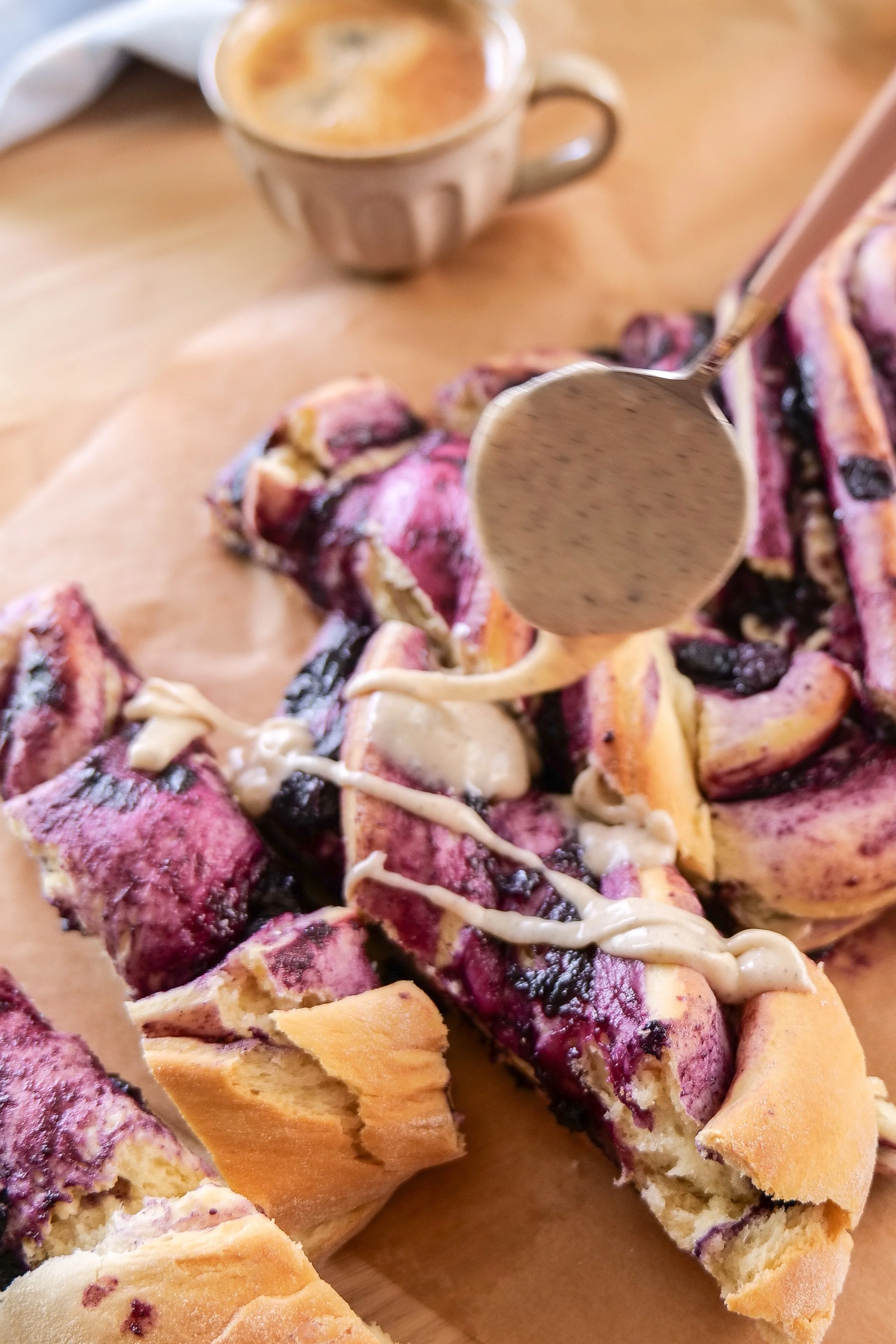 Brown butter vanilla icing drizzled over a warm homemade blueberry cinnamon roll loaf.
