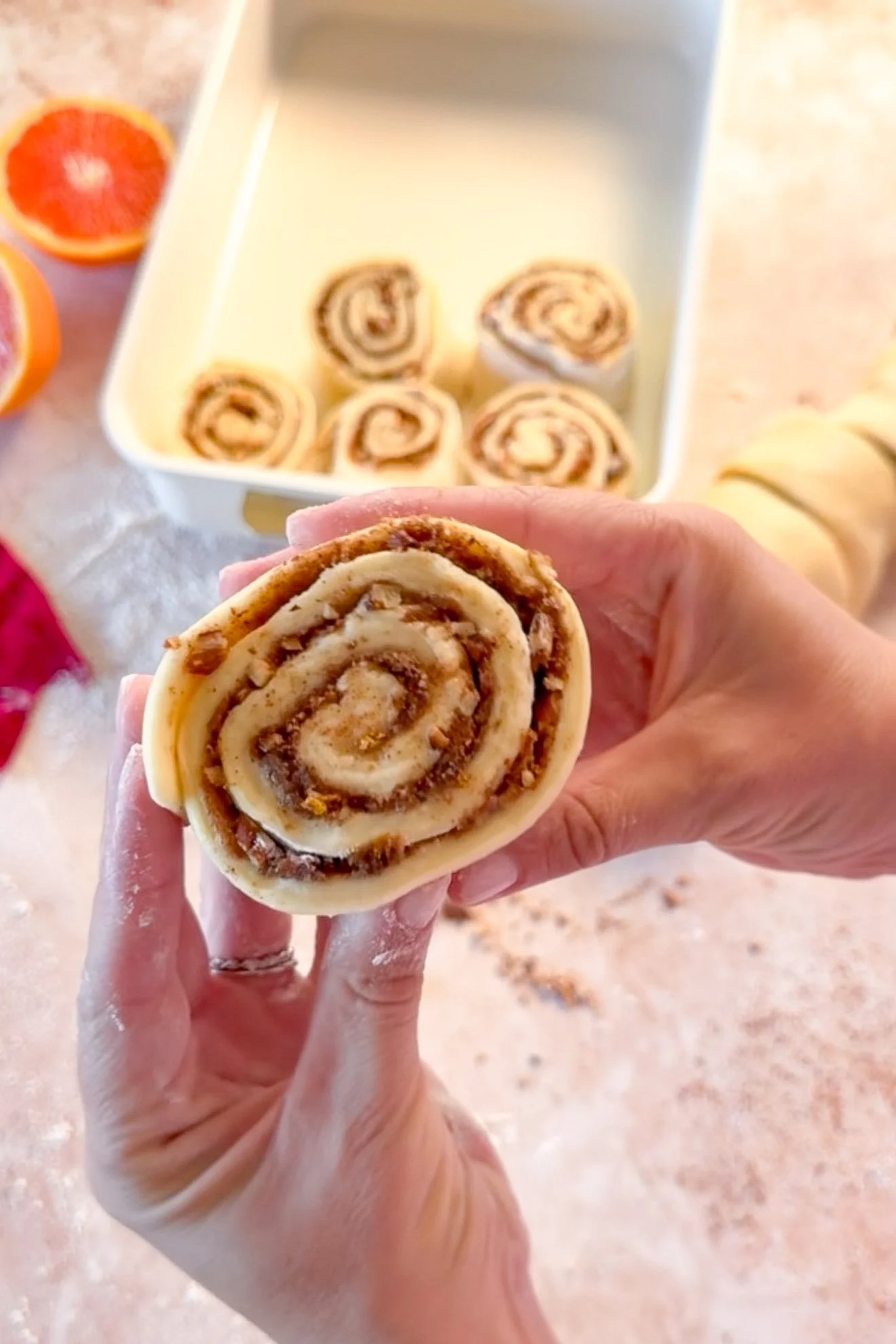 Unbaked orange pecan cinnamon rolls arranged in a baking dish before rising and baking.