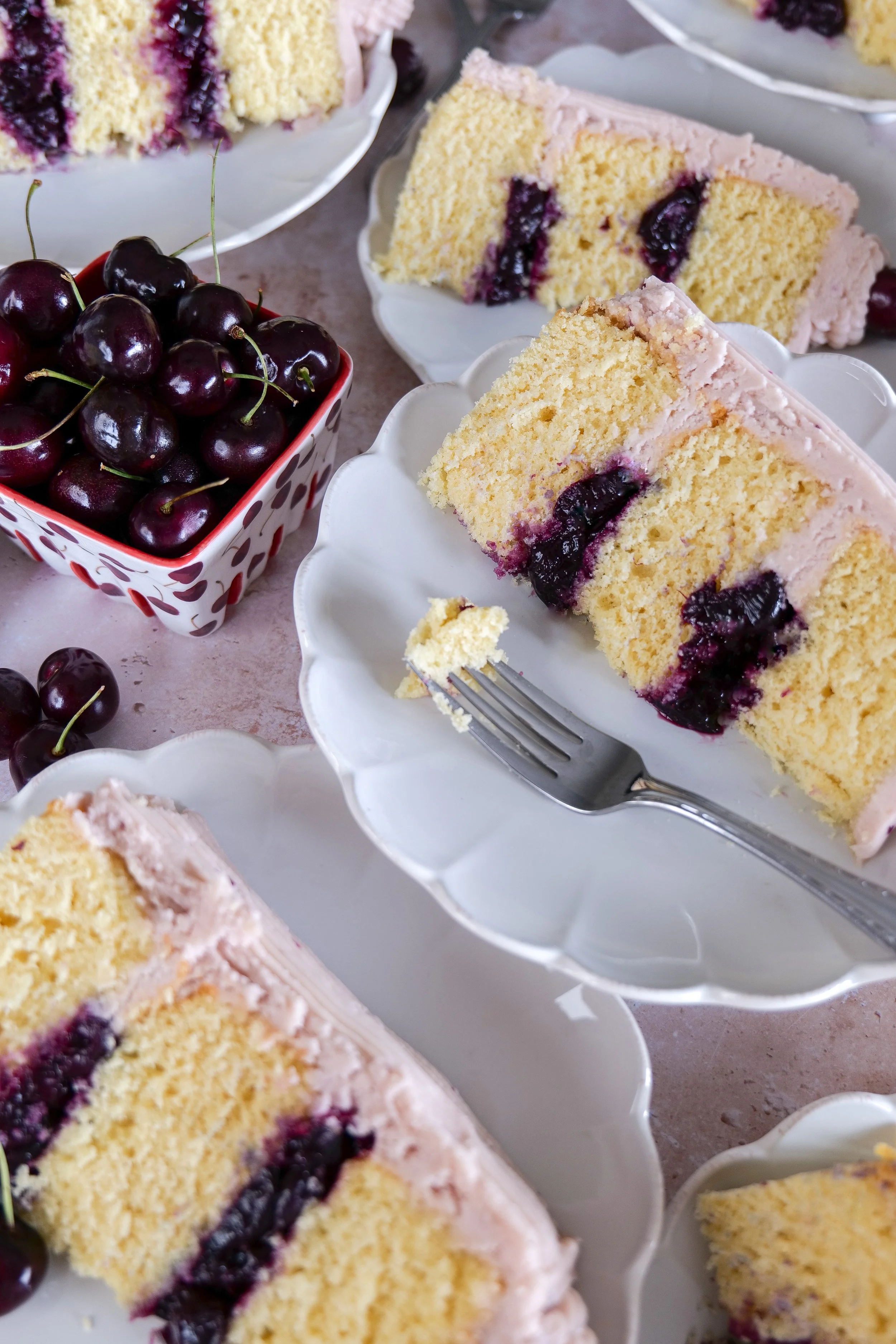 Easy homemade vanilla bean cherry layer cake recipe with fresh cherries and pink buttercream frosting.