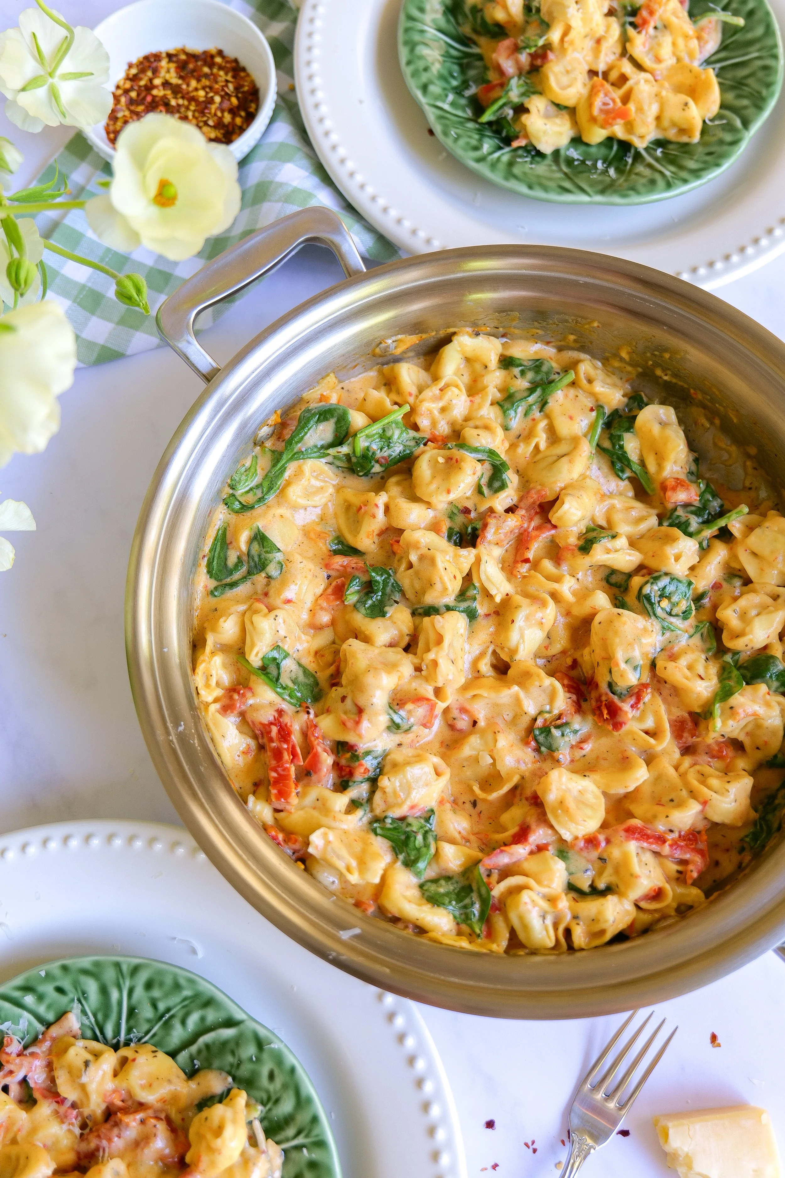 serving One Pot Marry Me Tortellini straight from the pan onto dinner plates