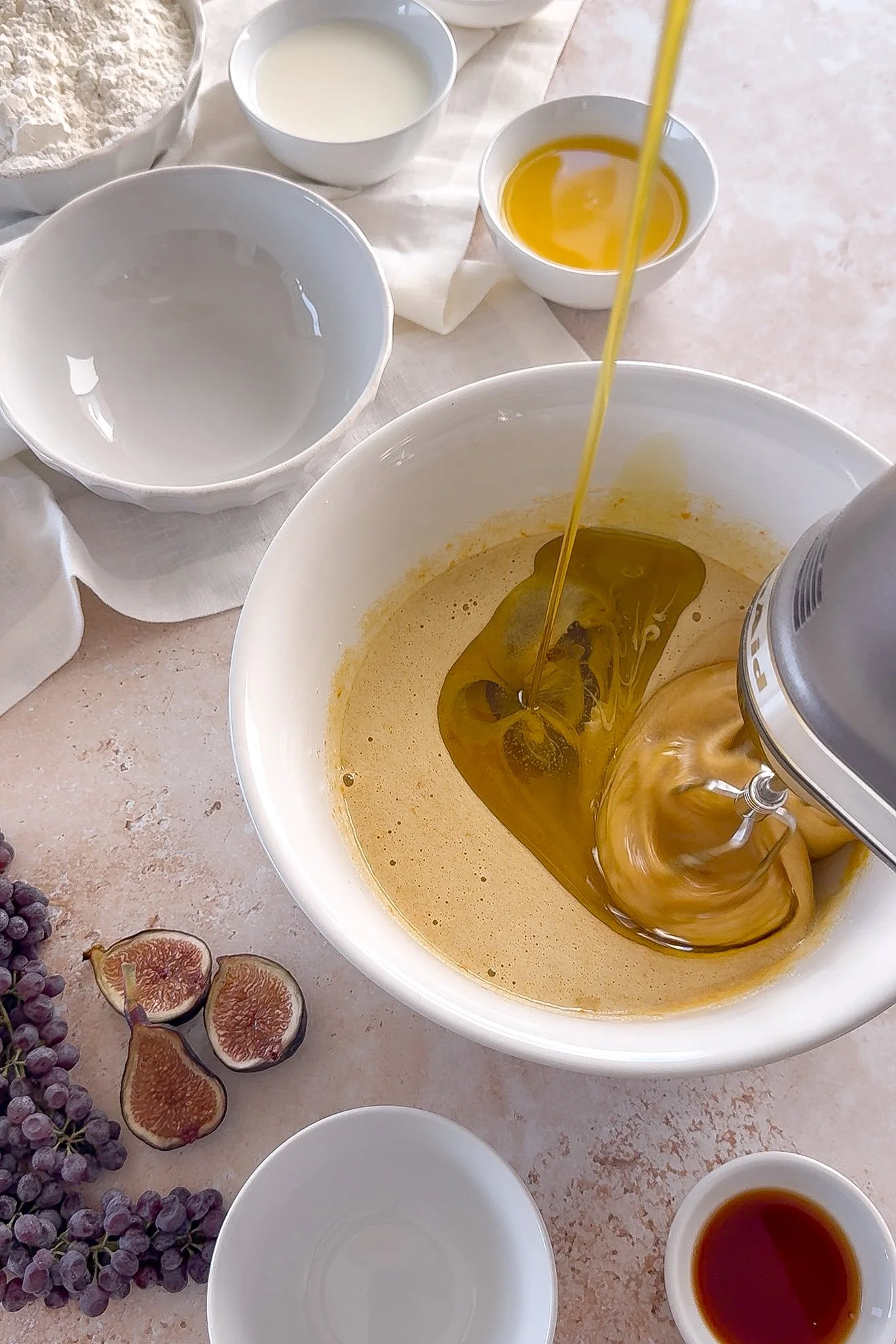 Extra virgin olive oil being poured into orange olive oil cake batter