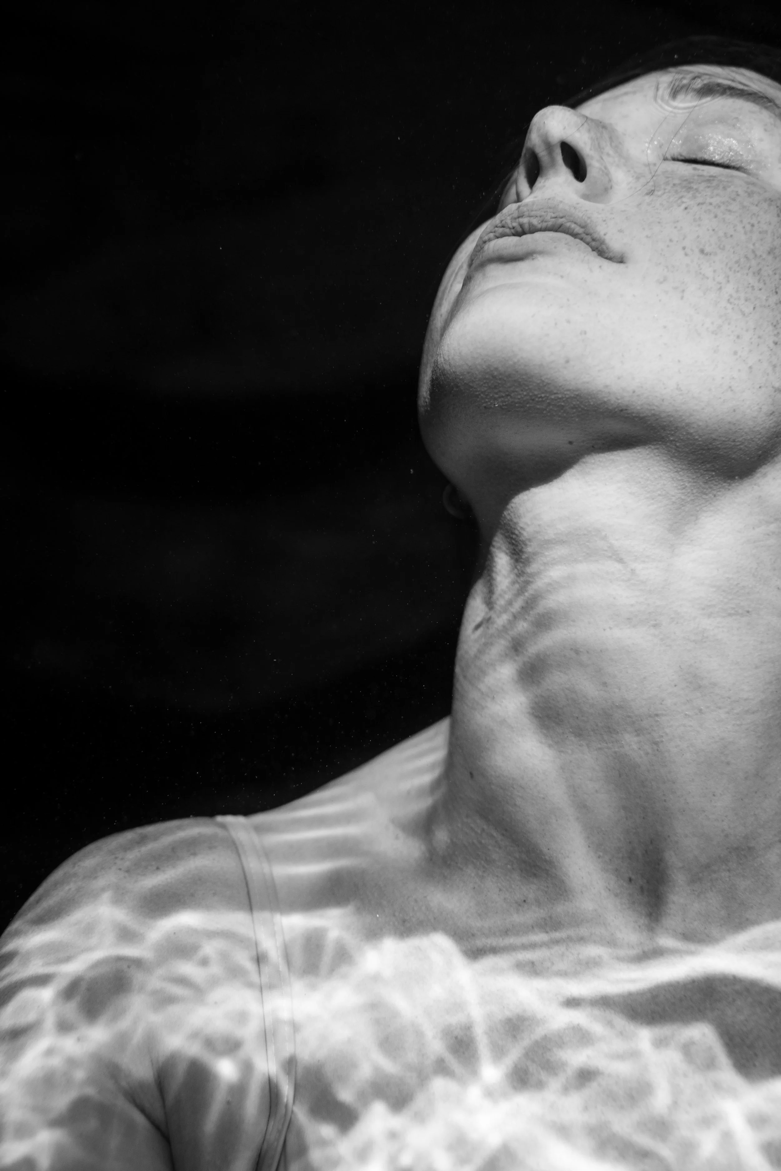 Black and white close-up portrait with reflected water light and sculptural shadow