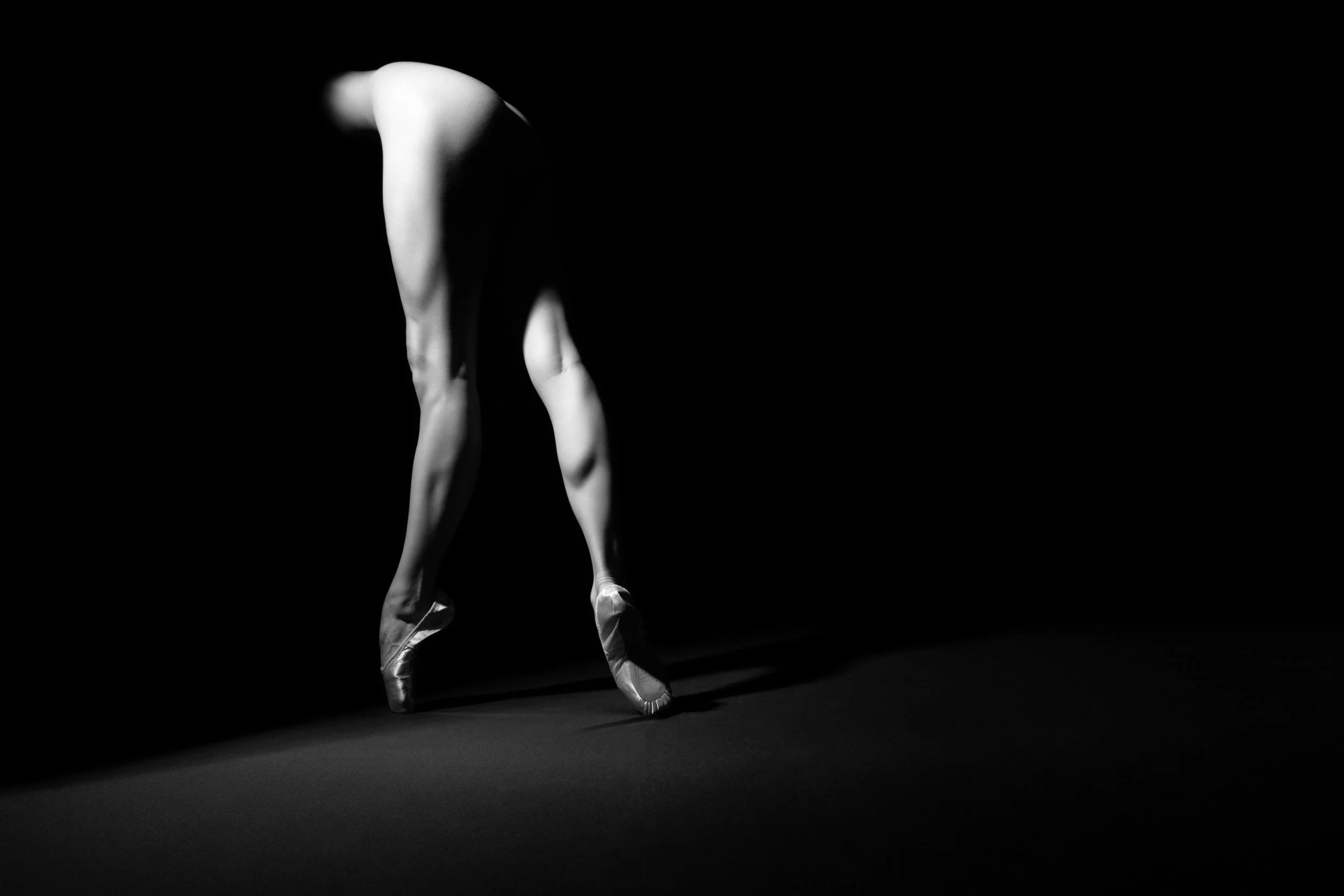 Minimal black and white fine art photograph of a ballet figure suspended within shadow