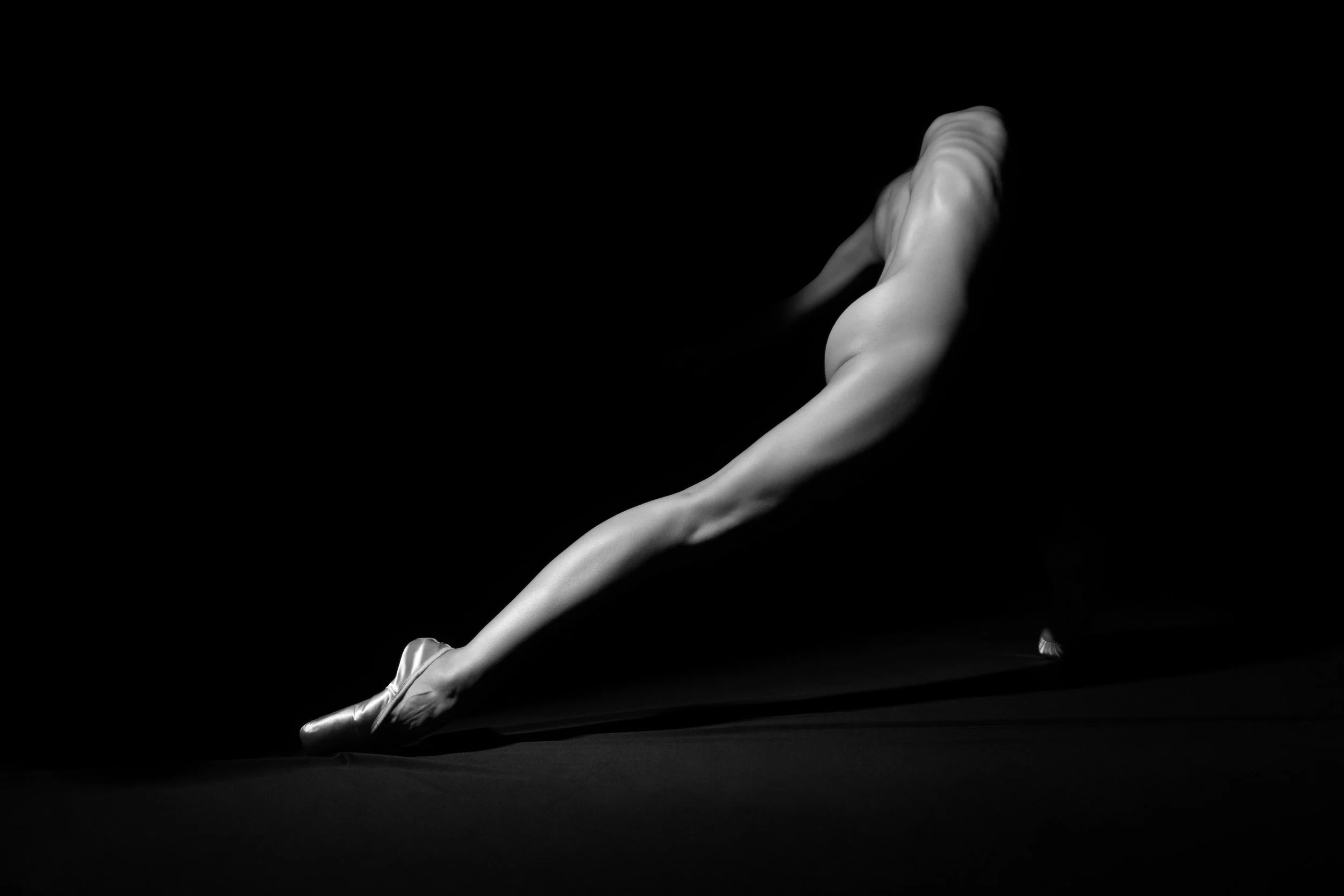 Abstract black and white ballet photograph of an elongated figure extending through negative space