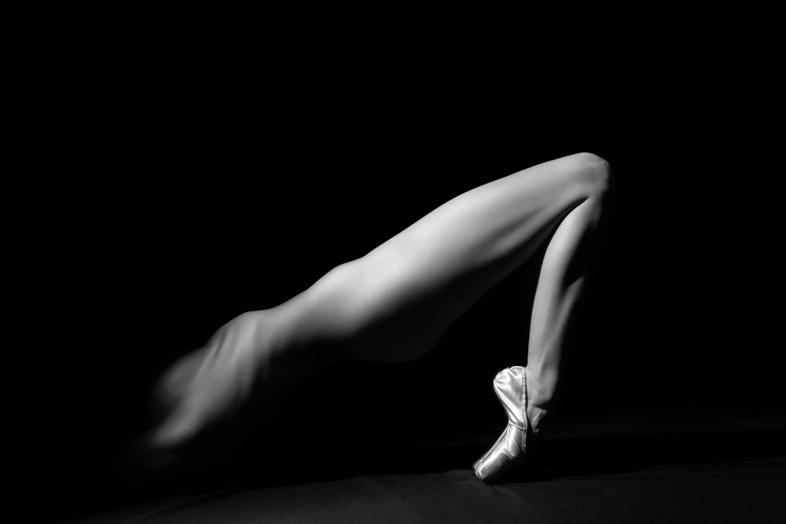 Fine art black and white photograph of an angular ballet form fading into black space