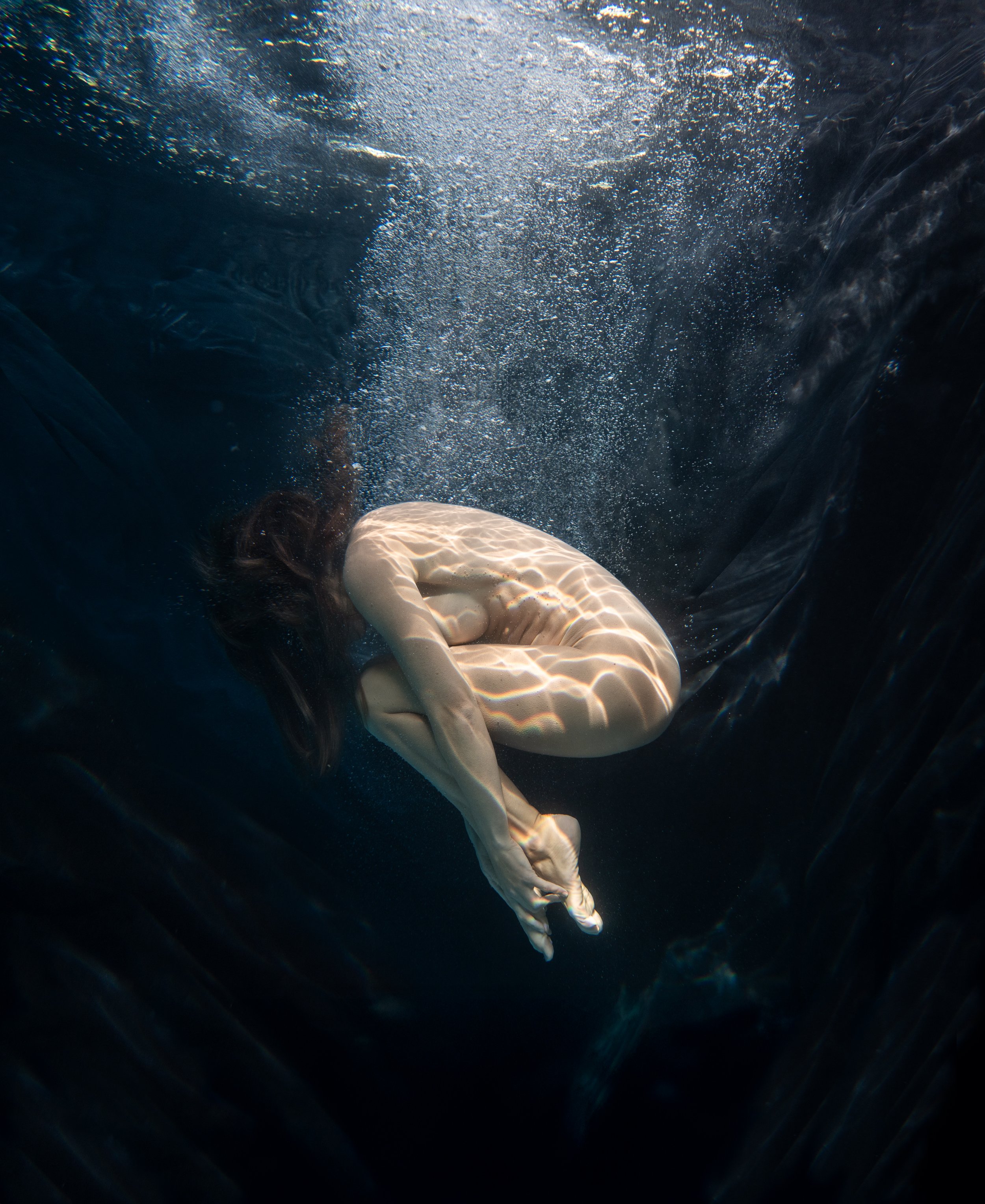 Underwater figure suspended in motion with cinematic light and flowing water
