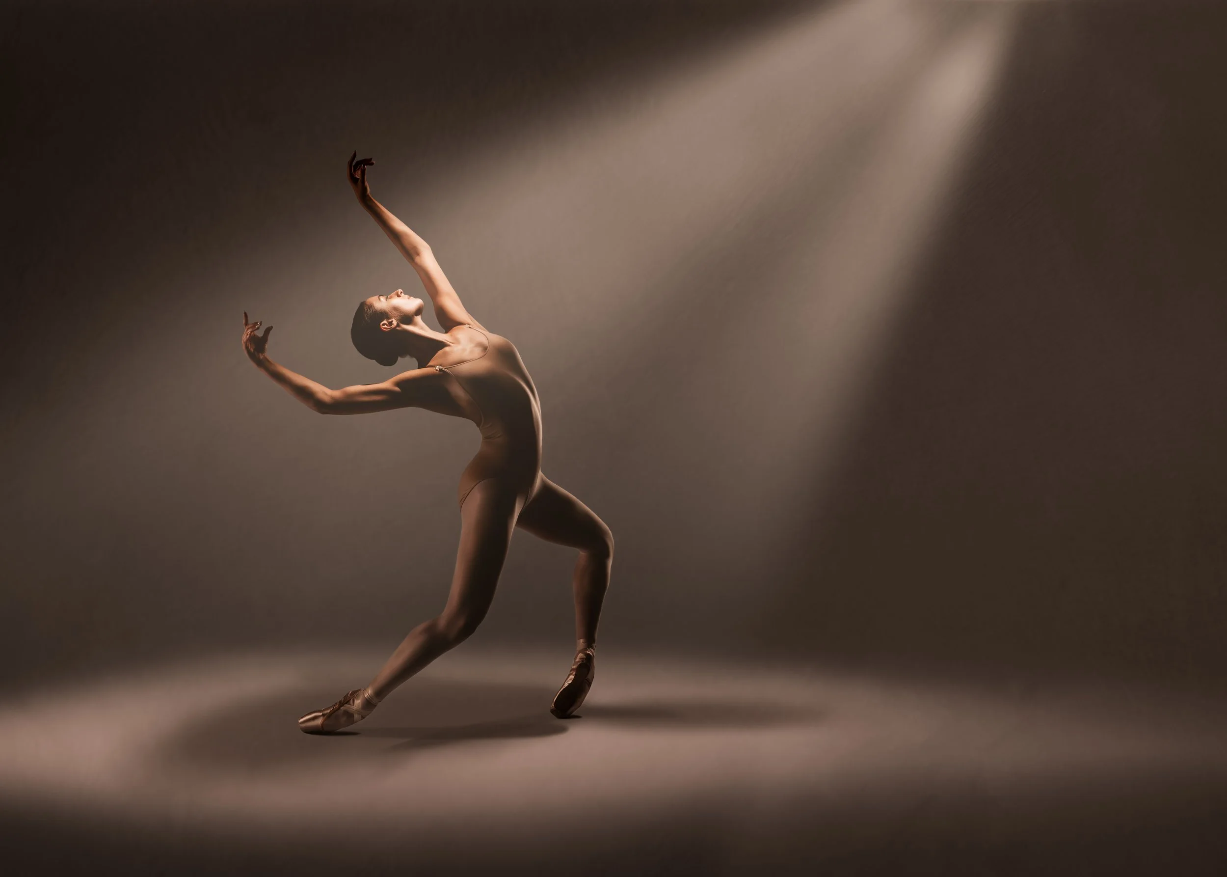Fine art dance figure illuminated by dramatic spotlight with expressive movement