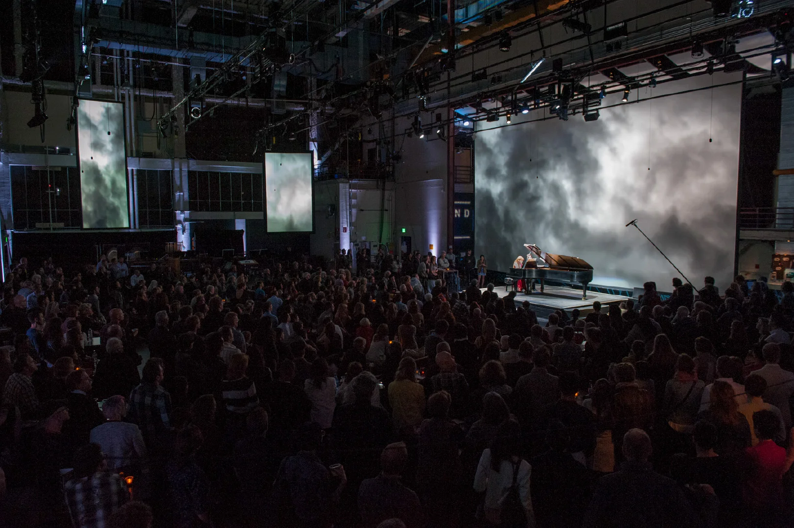 SoundBox venue during performance, taken from within main venue. Visible hanging microphones are part of Meyer Constellation acoustic sound system, processing natural sound into a flexible virtual acoustic “cloak” for the room.