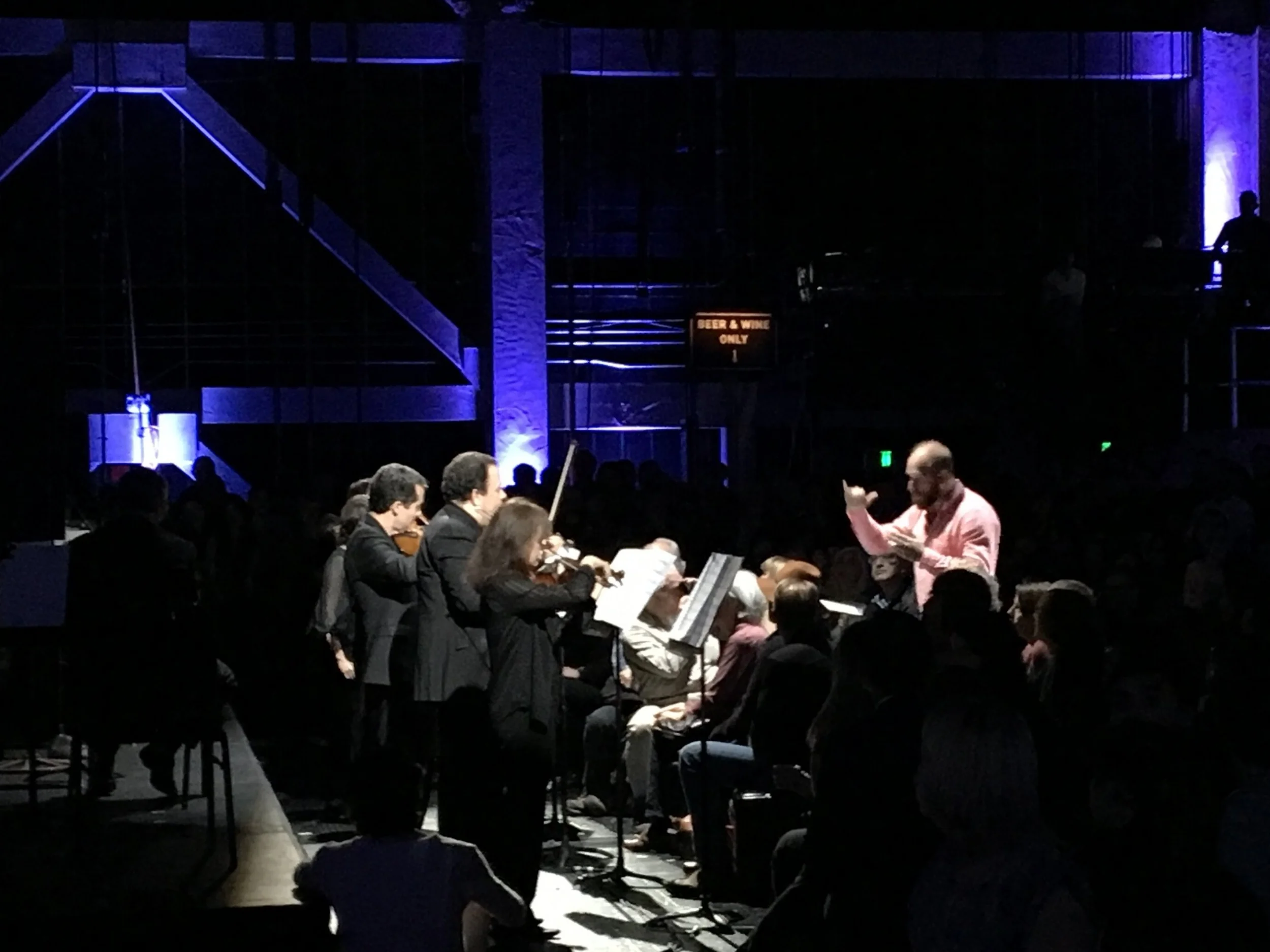 Conductor Christopher Rountree conducts from within the crowd, as violinists from the SF Symphony line the front row of the house for a stentorian performance.