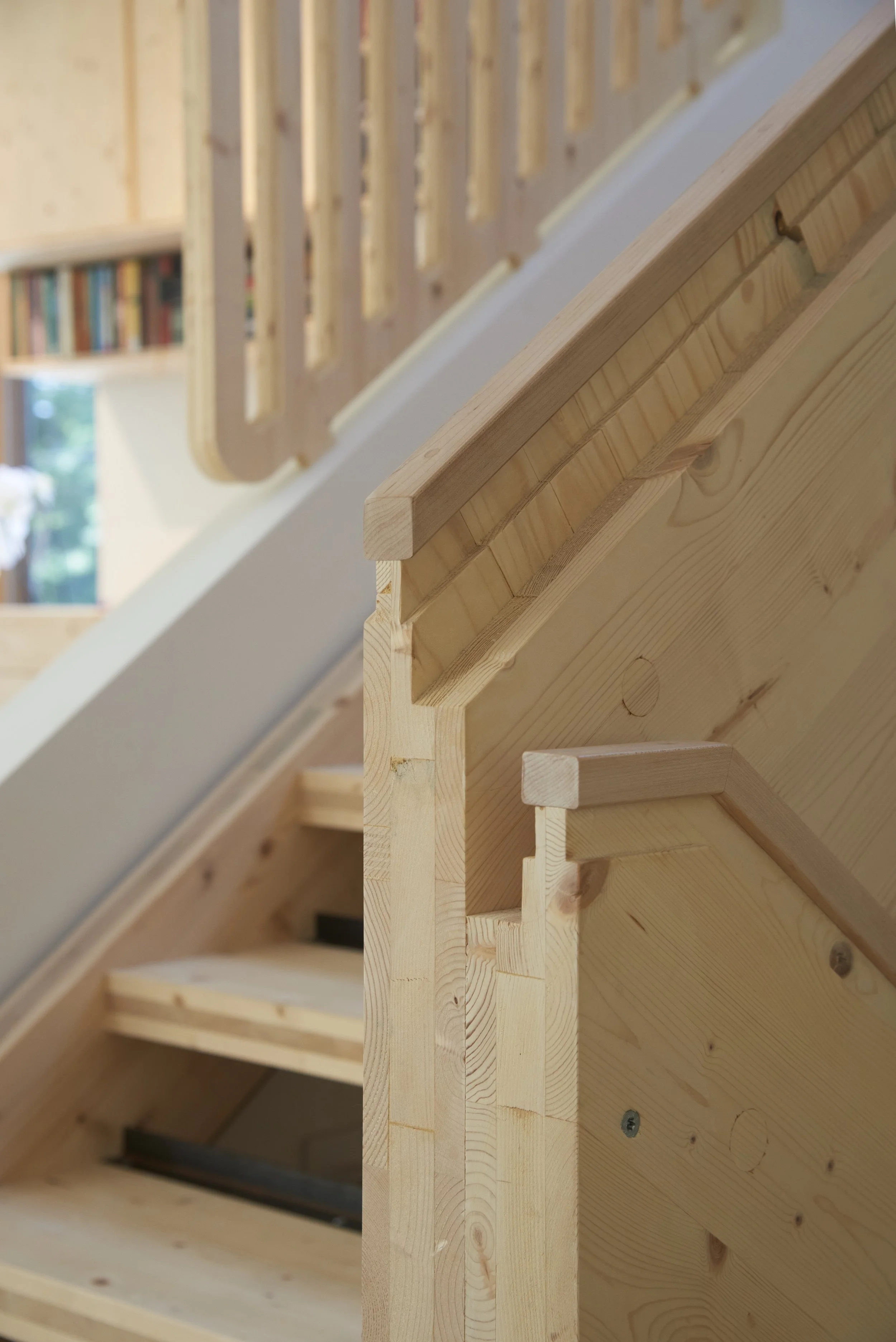 The CLT staircase is central to the design of the home, literally and figuratively, with its pale wood tones echoed in the flooring and cabinetry throughout the house. It ascends from the basement all the way up to the third floor.