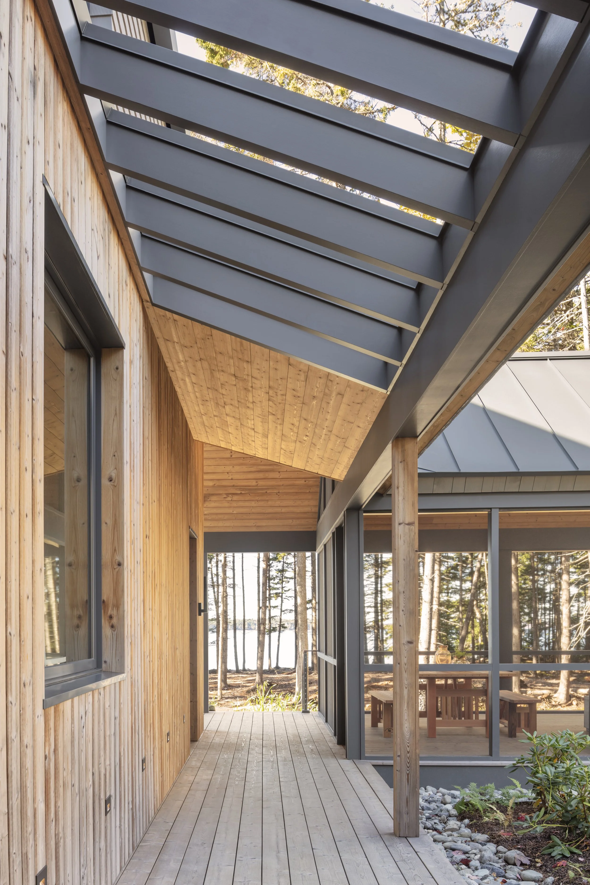  A wide walkway runs the length of the facade that faces the driveway. The direct sightline through to the grove of trees and the water beyond draws the eye deeper into nature with every step. 