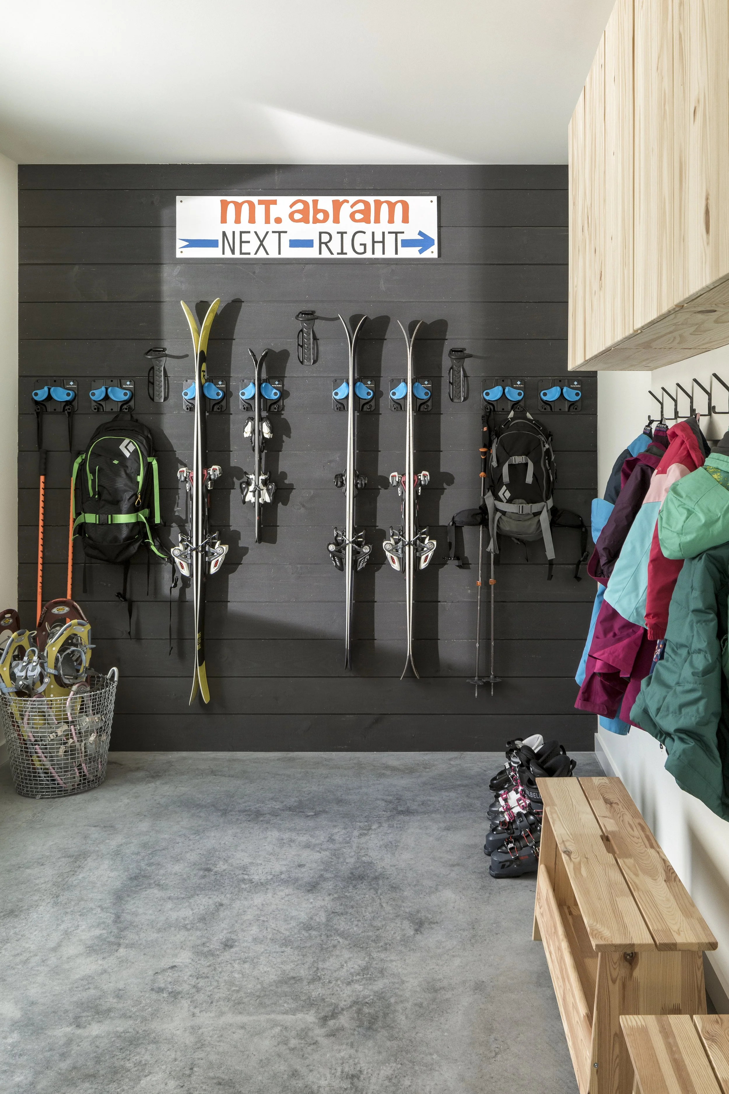 Inside the gear room, a variety of skis, snowshoes, and winterwear are neatly organized
