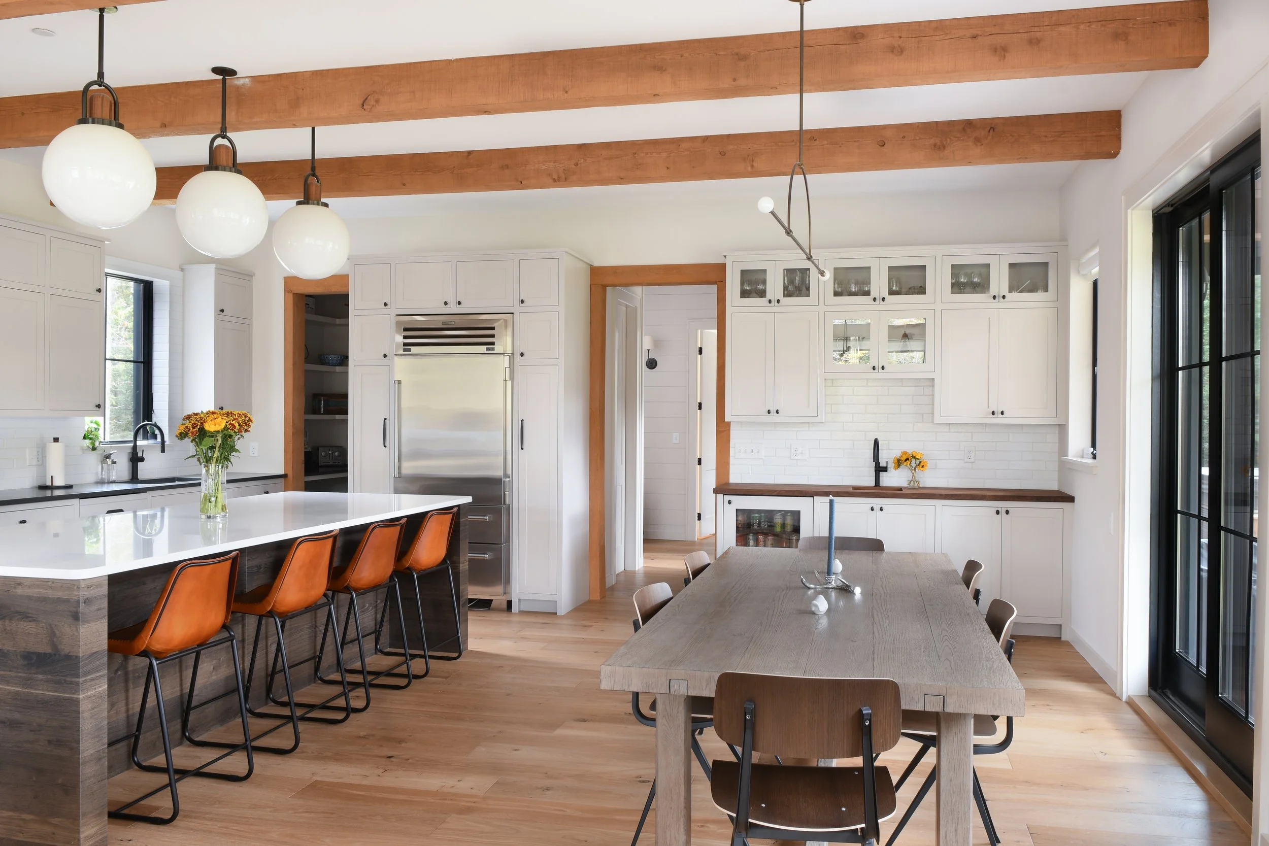 The kitchen features wood beams, white cabinets, and dark wood furniture.